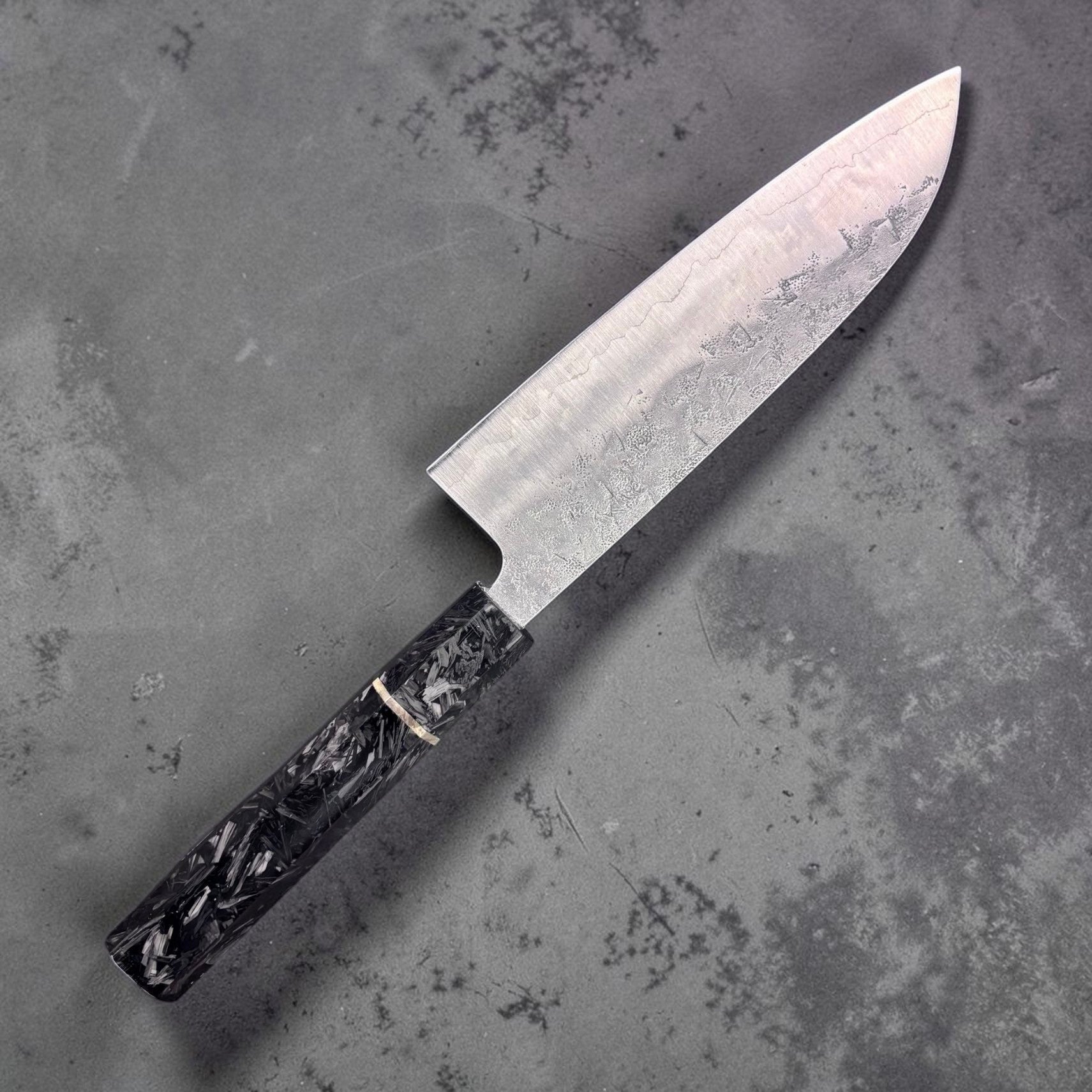 Tokushu Knife SLD Washiji Santoku upside down showing non marked side on grey blurred background.