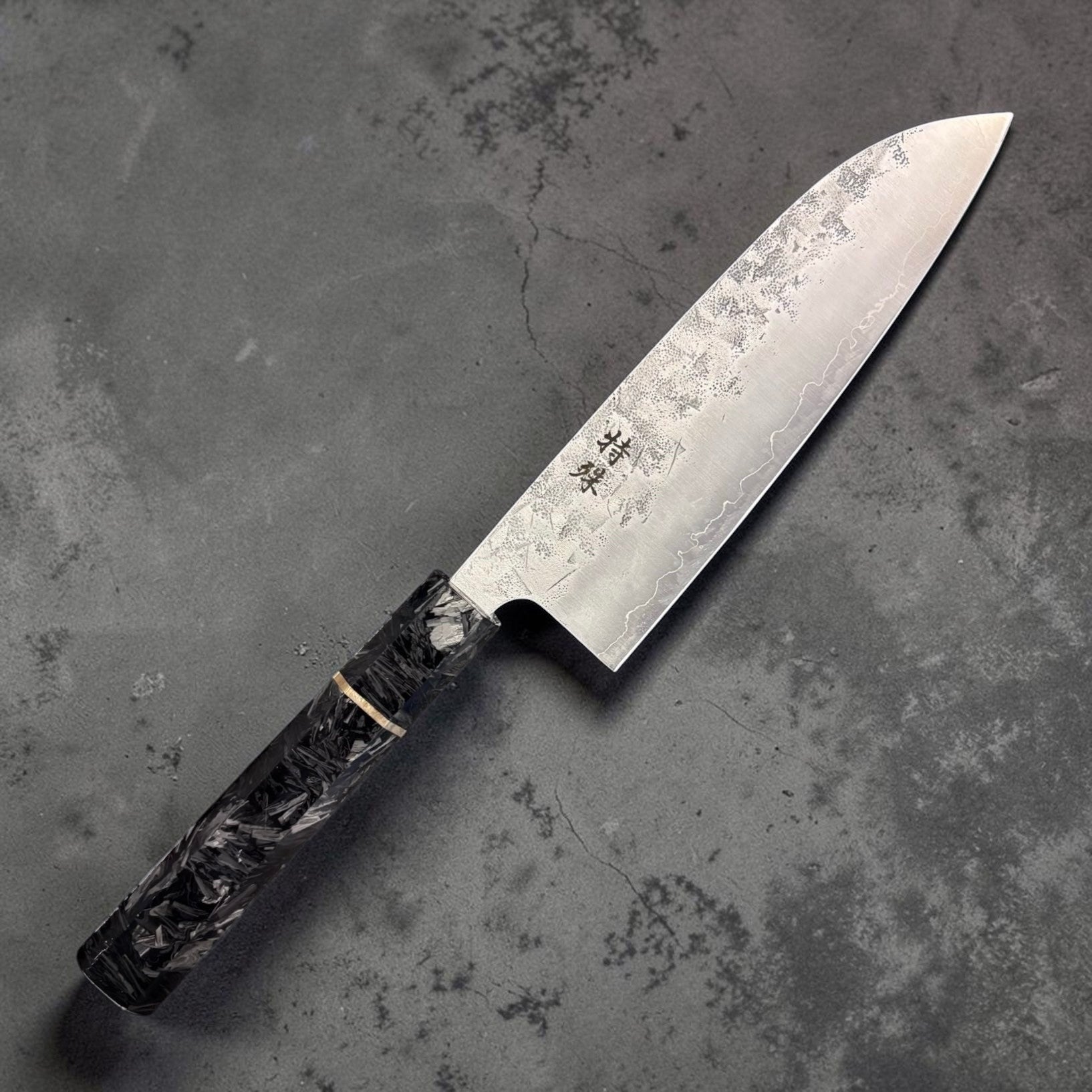 Tokushu Knife SLD Washiji Santoku showing off kanji on grey blurred background.