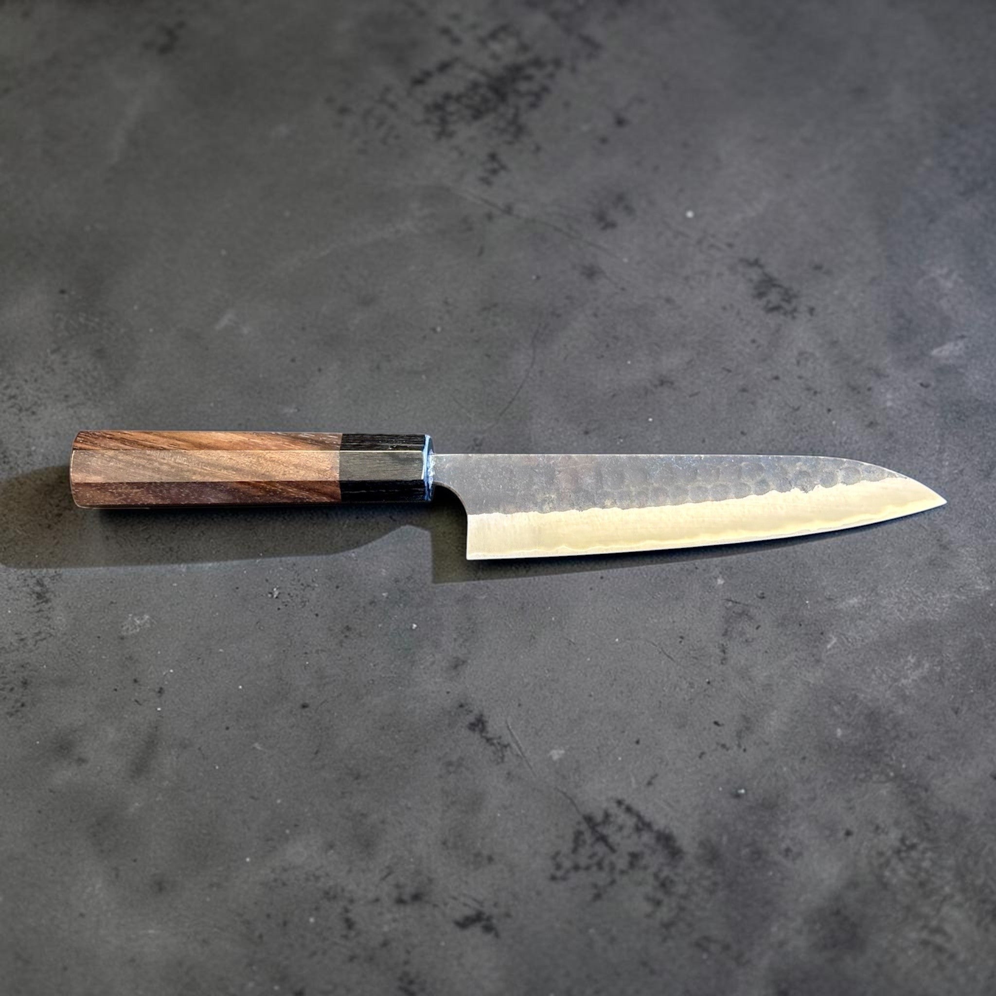 Anryu Aogami Super Kuro Tsuchime Petty 150 mm with rosewood octagon handle, reverse full profile emphasizing the kurouchi tsuchime texture and satin edge line.