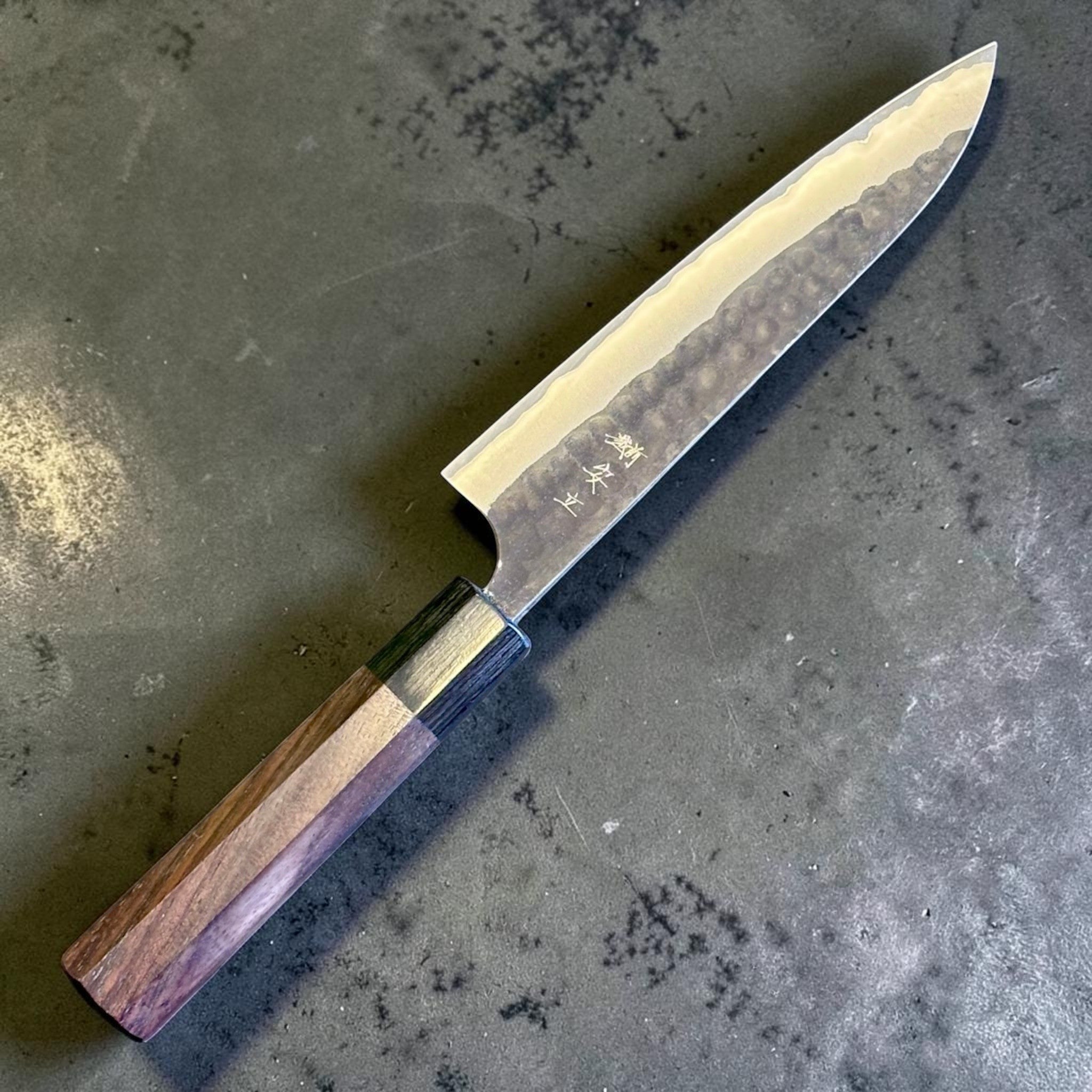 Anryu Aogami Super Kuro Tsuchime Petty 150 mm with rosewood octagon handle, opposite angled beauty shot showing the kanji engraving and hammered cladding.