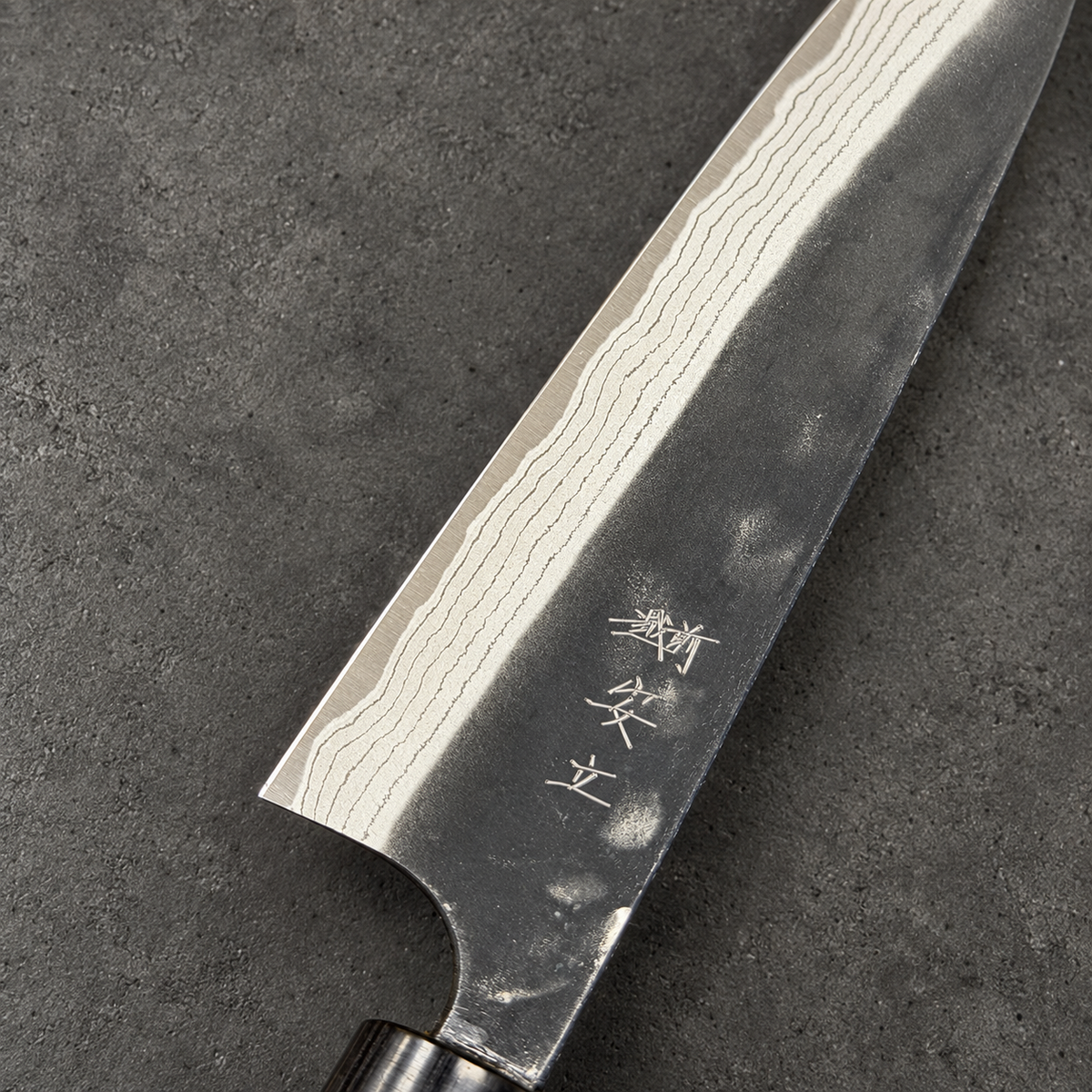 Close-up of Anryu petty knife engraving, layered Damascus bevel and kurouchi finish