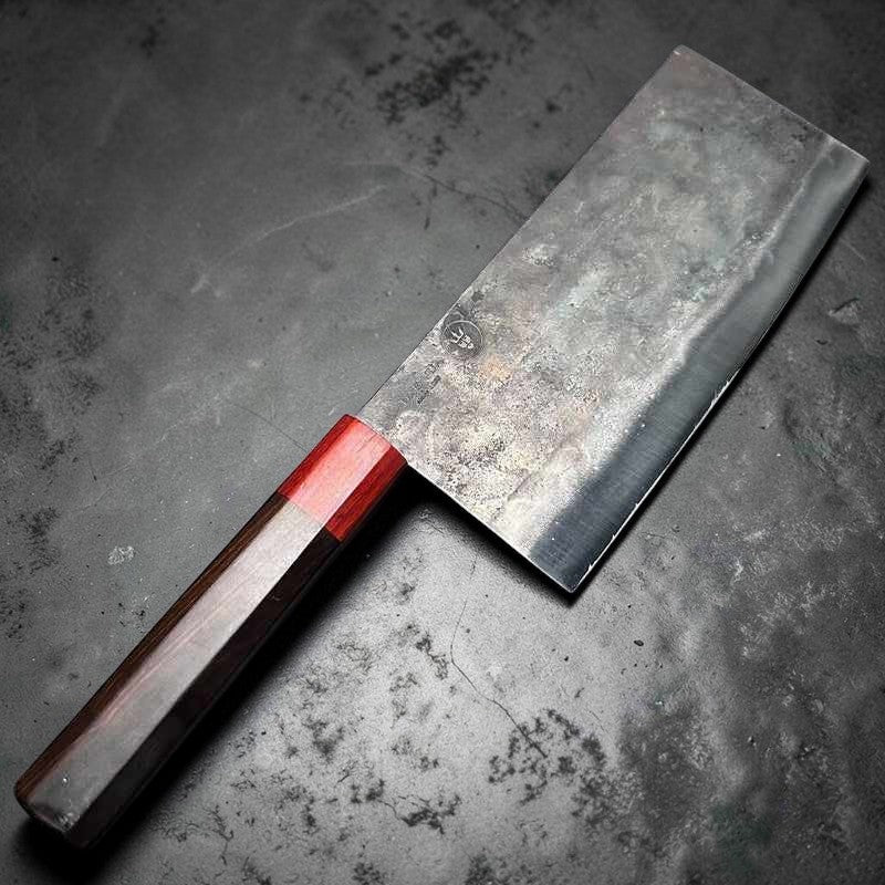 The DAO VUA V3 52100 Chinese Cleaver with its distinctive red handle, resting on a dark countertop