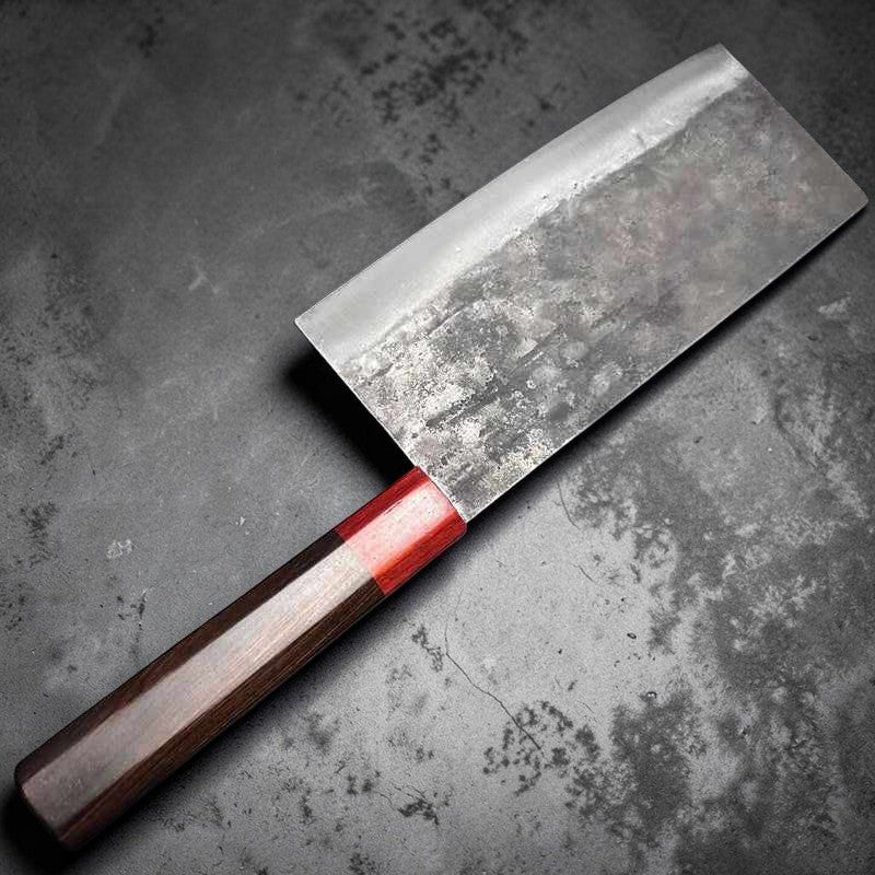 Close-up of the DAO VUA V3 52100 Chinese Cleaver's blade and red handle on a wooden table