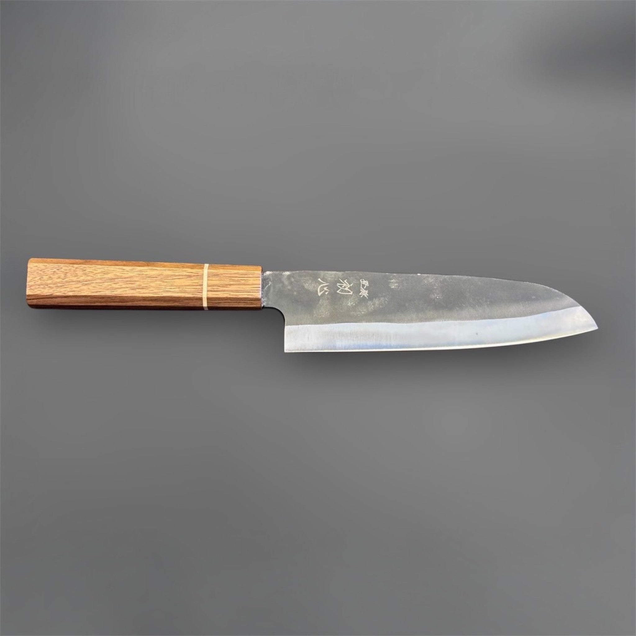 Hatsukokoro Aokitae Blue #2 Kurouchi Santoku 180 mm with Sanjo walnut handle and maple stripe, angled back side view showing the grind and blade profile.