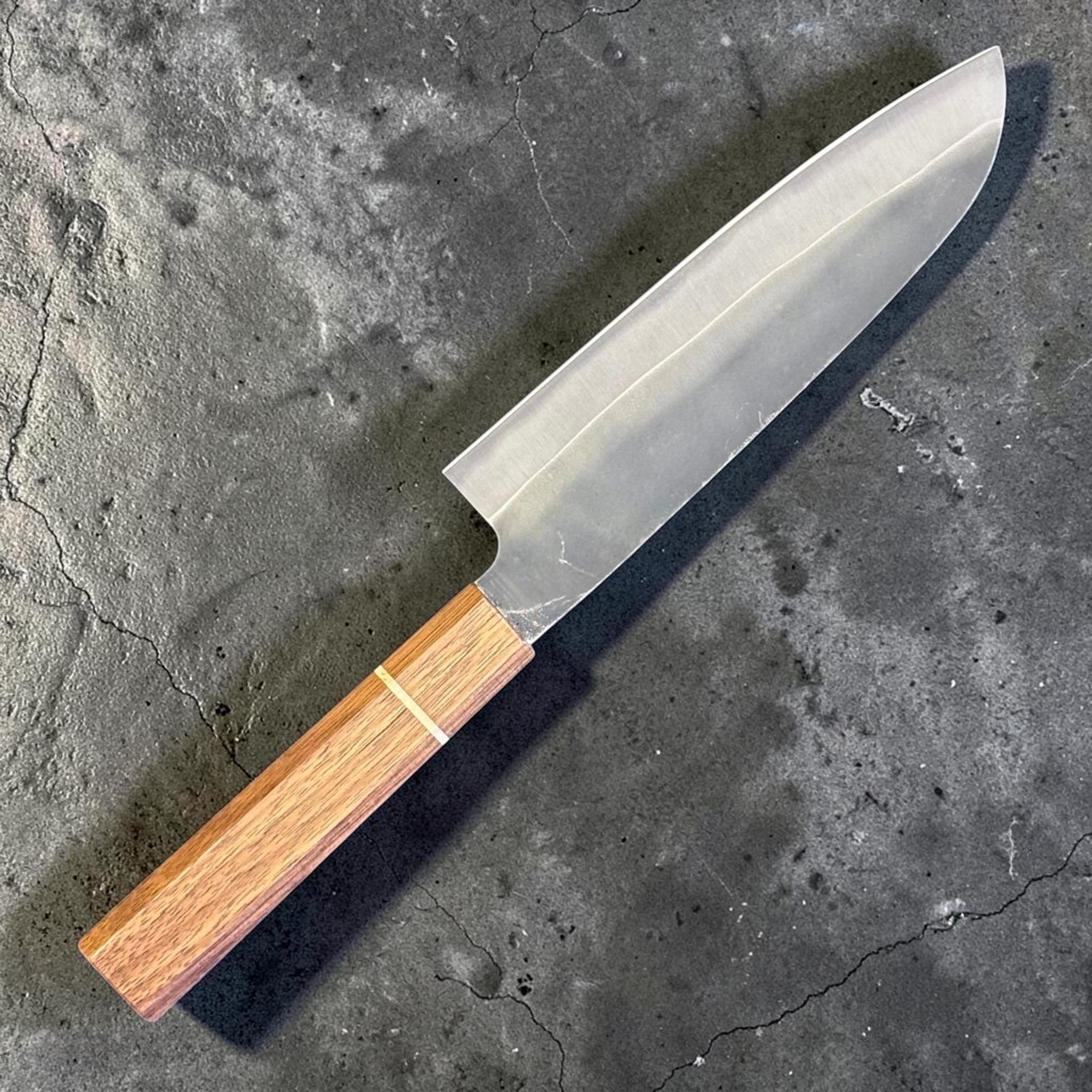 Hatsukokoro Aokitae Blue #2 Kurouchi Santoku 180 mm with Sanjo walnut handle and maple stripe, angled back side view showing the grind and blade profile.