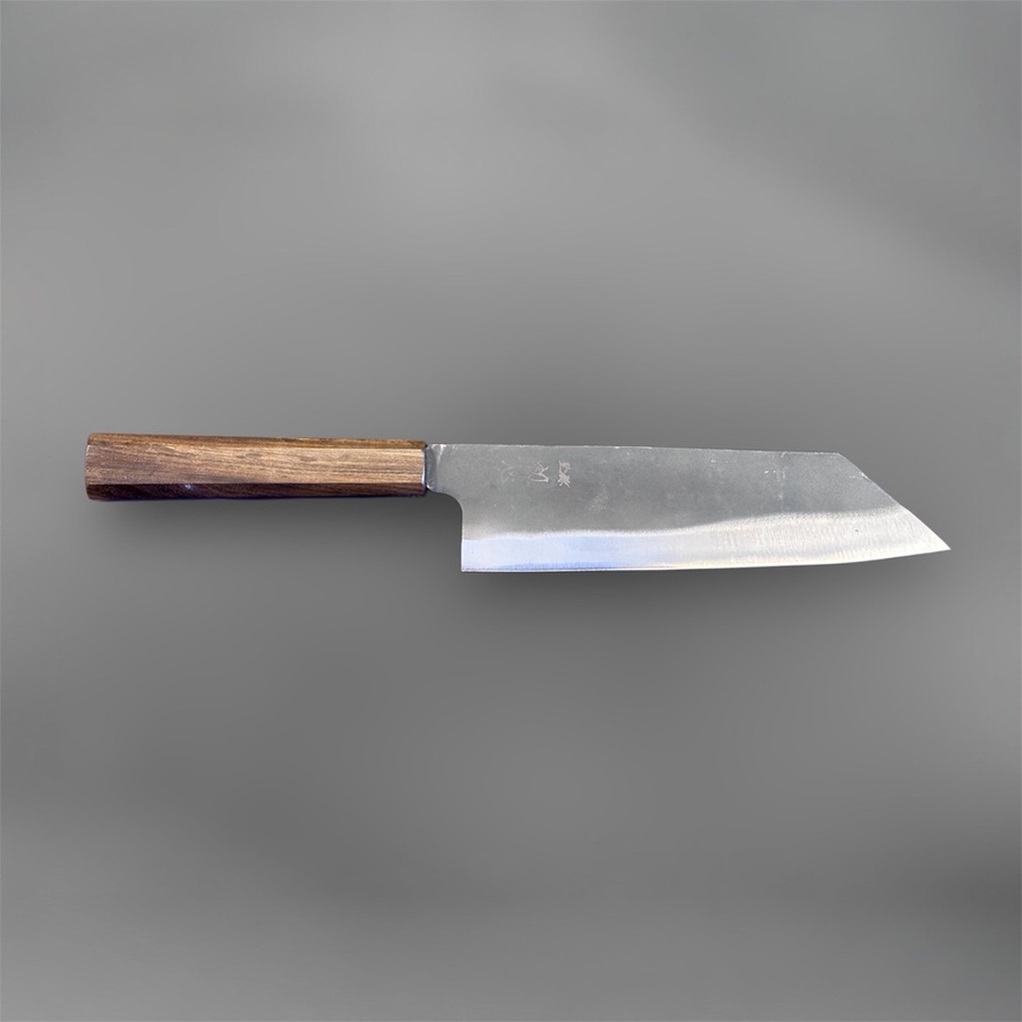 Hatsukokoro Blue #2 Kurouchi Bunka 190 mm with mono ebony handle, full profile front-side view on gray background showing the long bunka edge line, pronounced reverse tanto tip, and traditional wa handle.