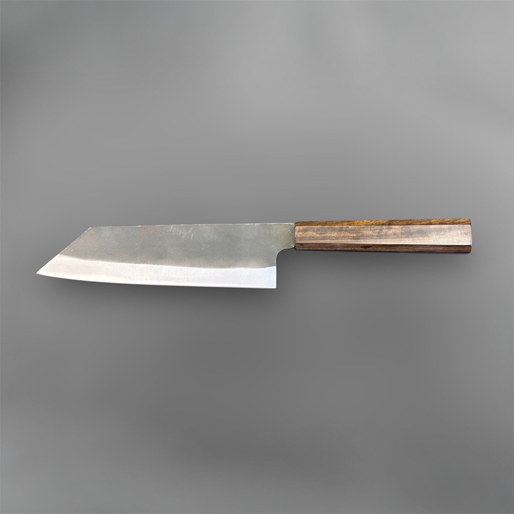 Hatsukokoro Blue #2 Kurouchi Bunka 190 mm with mono ebony handle, full profile back-side view showing the blade geometry, kurouchi finish, and clean contrast between the dark upper blade and polished cutting edge.