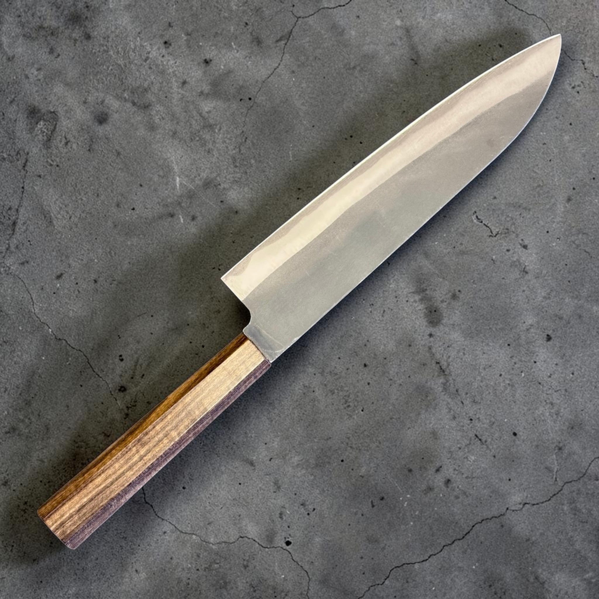 Hatsukokoro Blue #2 Kurouchi Gyuto 220 mm with mono ebony handle, angled view highlighting the kurouchi finish and edge line.