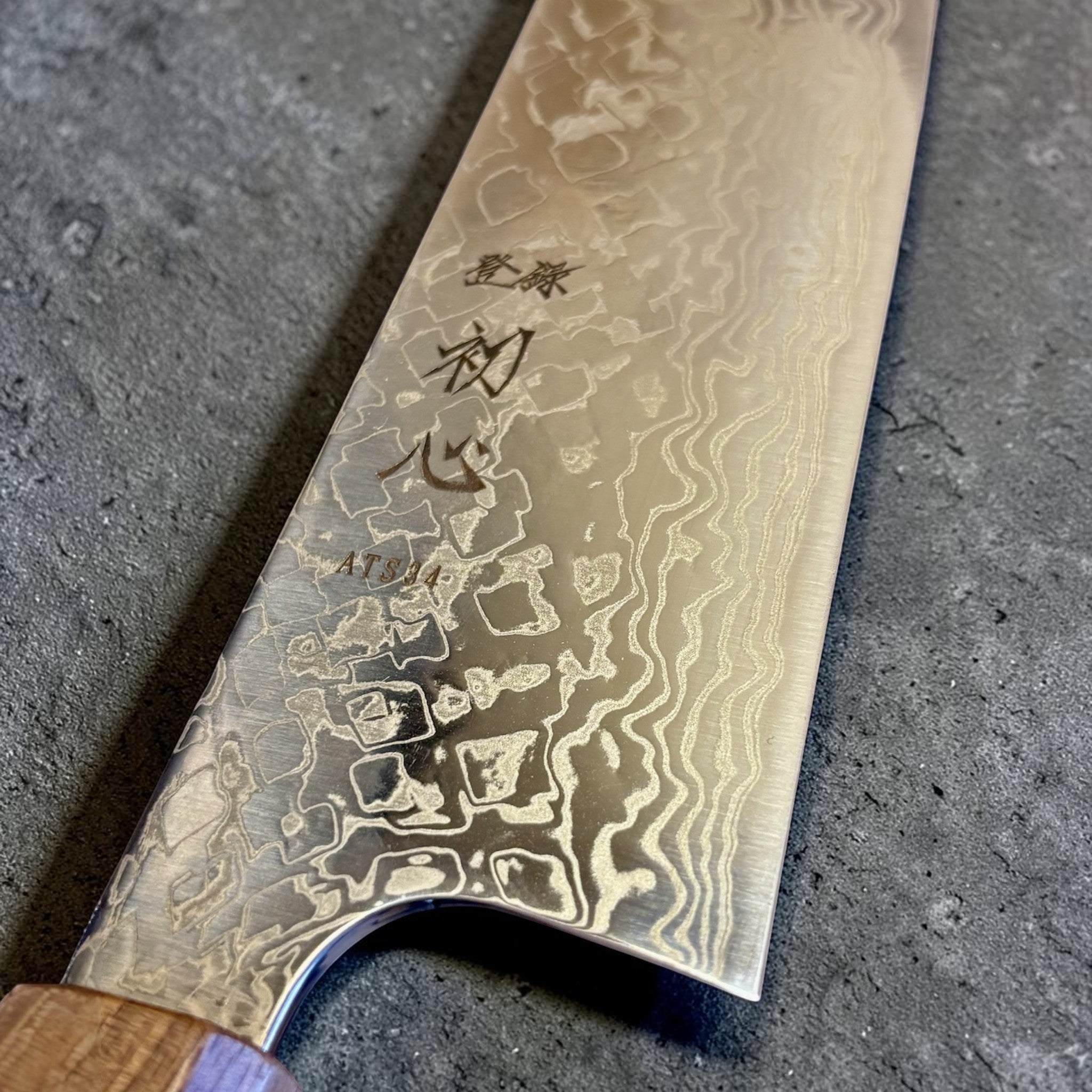 Hatsukokoro Ginga ATS-34 Nickel Damascus Bunka 170 mm with Sanjo walnut handle and maple stripe, close-up of the blade heel, engraving, and nickel Damascus detail.