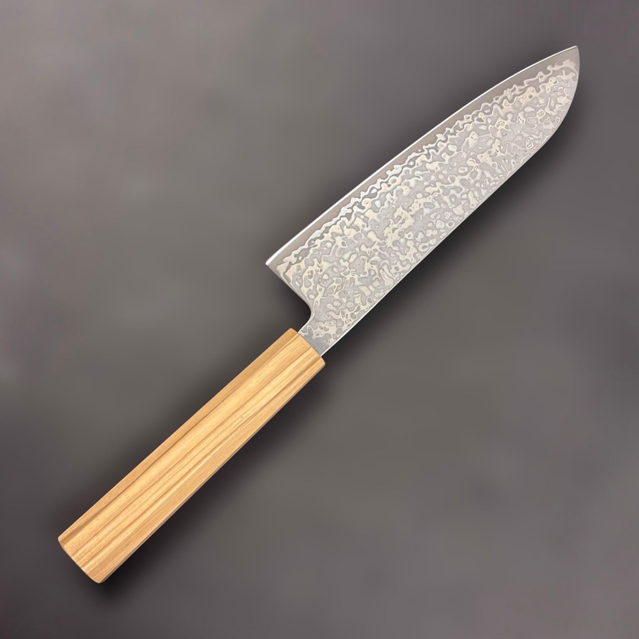 Hatsukokoro Hikari SLD Damascus Santoku 170 mm with olive wood handle, reverse angled shot; close-up of damascus pattern on the blade.