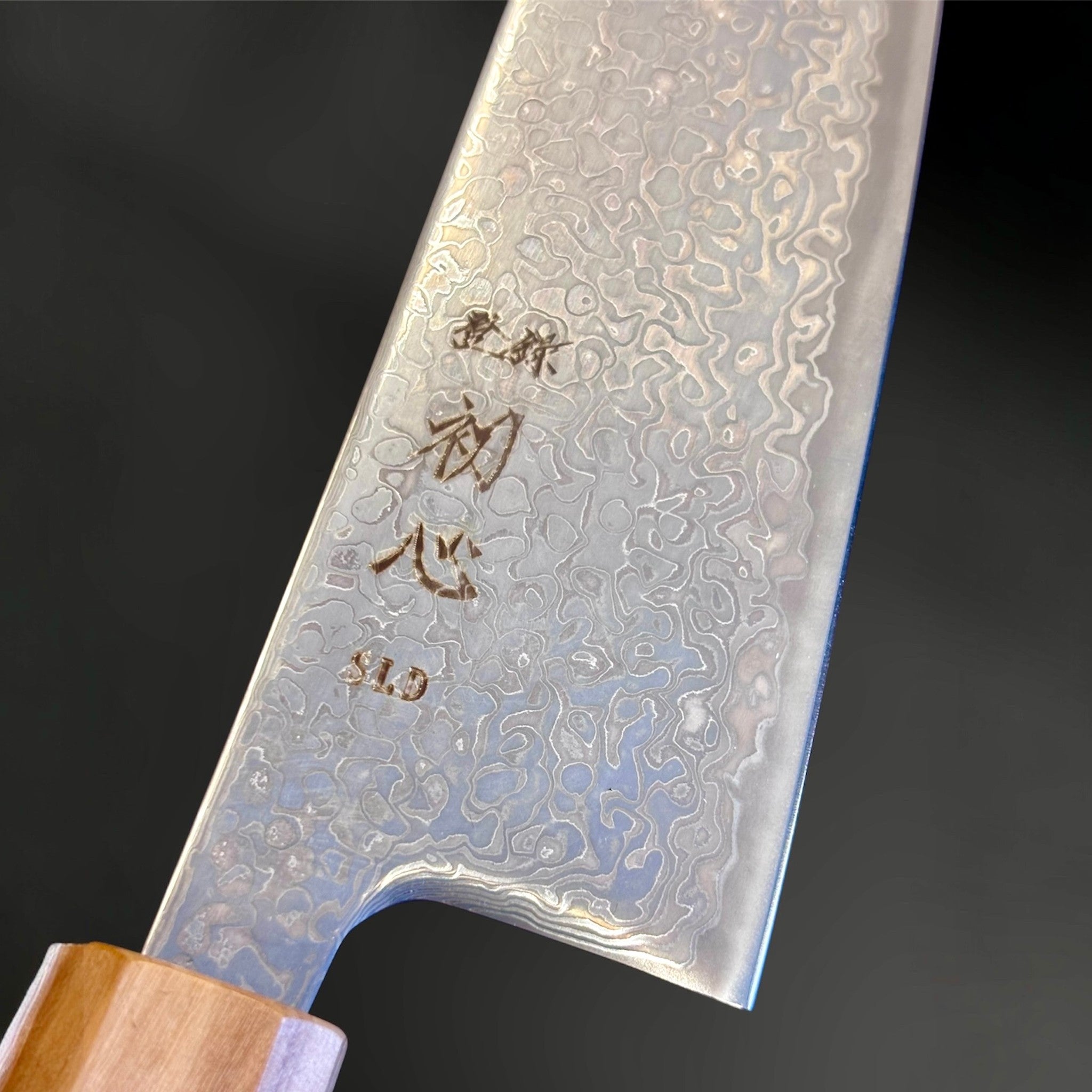 Hatsukokoro Hikari SLD Damascus Kurozome Bunka 170 mm with olive wood handle, close-up of kuro-zome damascus pattern and engraved blade details.