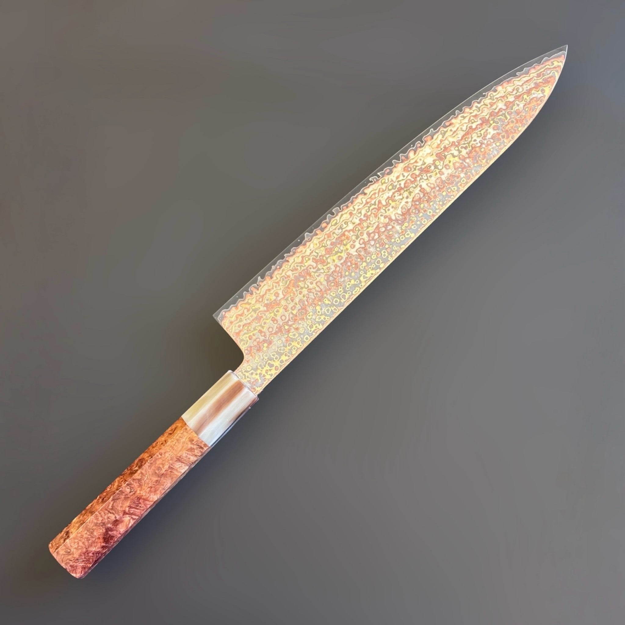 Hatsukokoro Hinotori V-Toku2 Rainbow Damascus Gyuto 240 mm with amboyna burl handle, angled studio view showing the rainbow Damascus pattern left side.