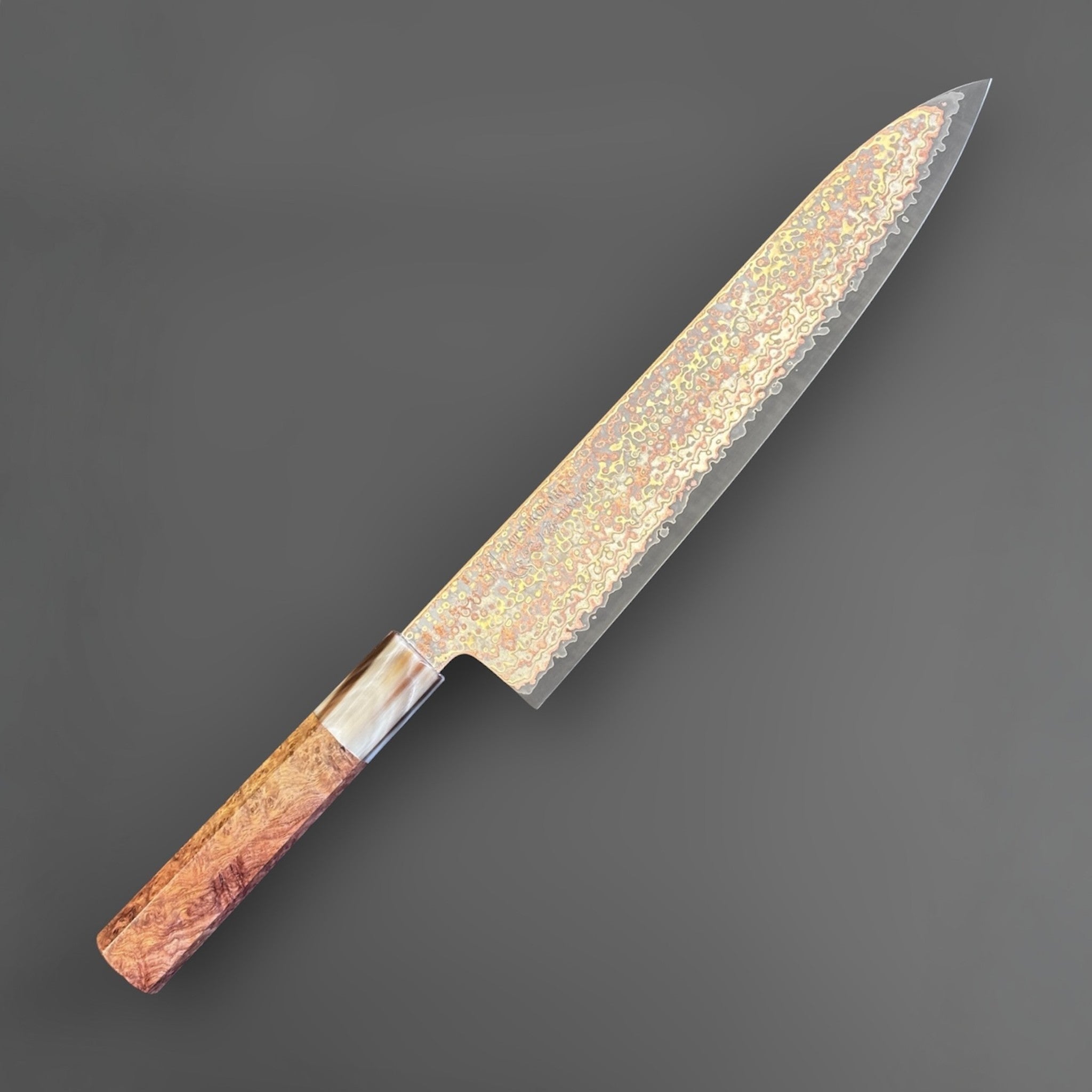 Hatsukokoro Hinotori V-Toku2 Rainbow Damascus Gyuto 240 mm with amboyna burl handle, angled studio view showing the rainbow Damascus pattern.
