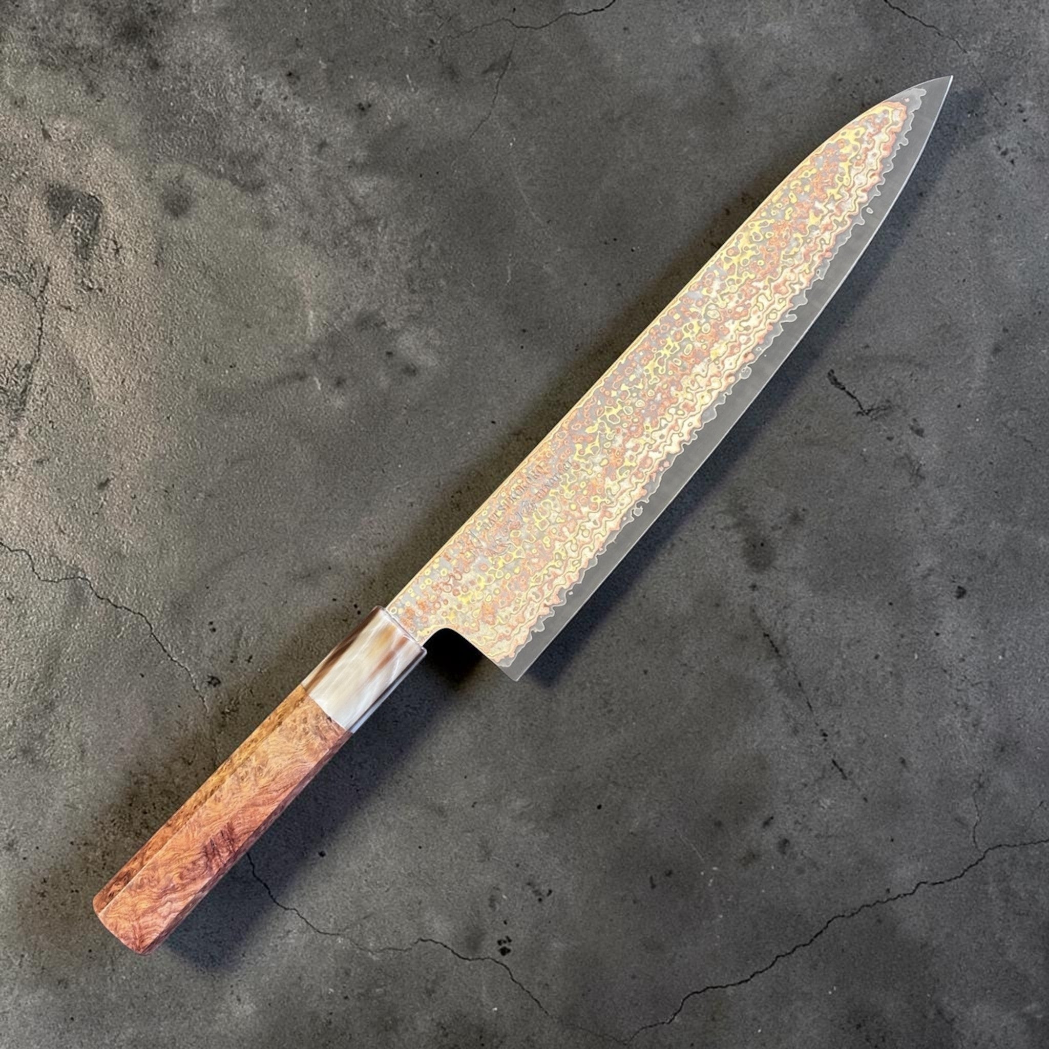 Hatsukokoro Hinotori V-Toku2 Rainbow Damascus Gyuto 240 mm with amboyna burl handle, angled studio view showing the rainbow Damascus pattern.