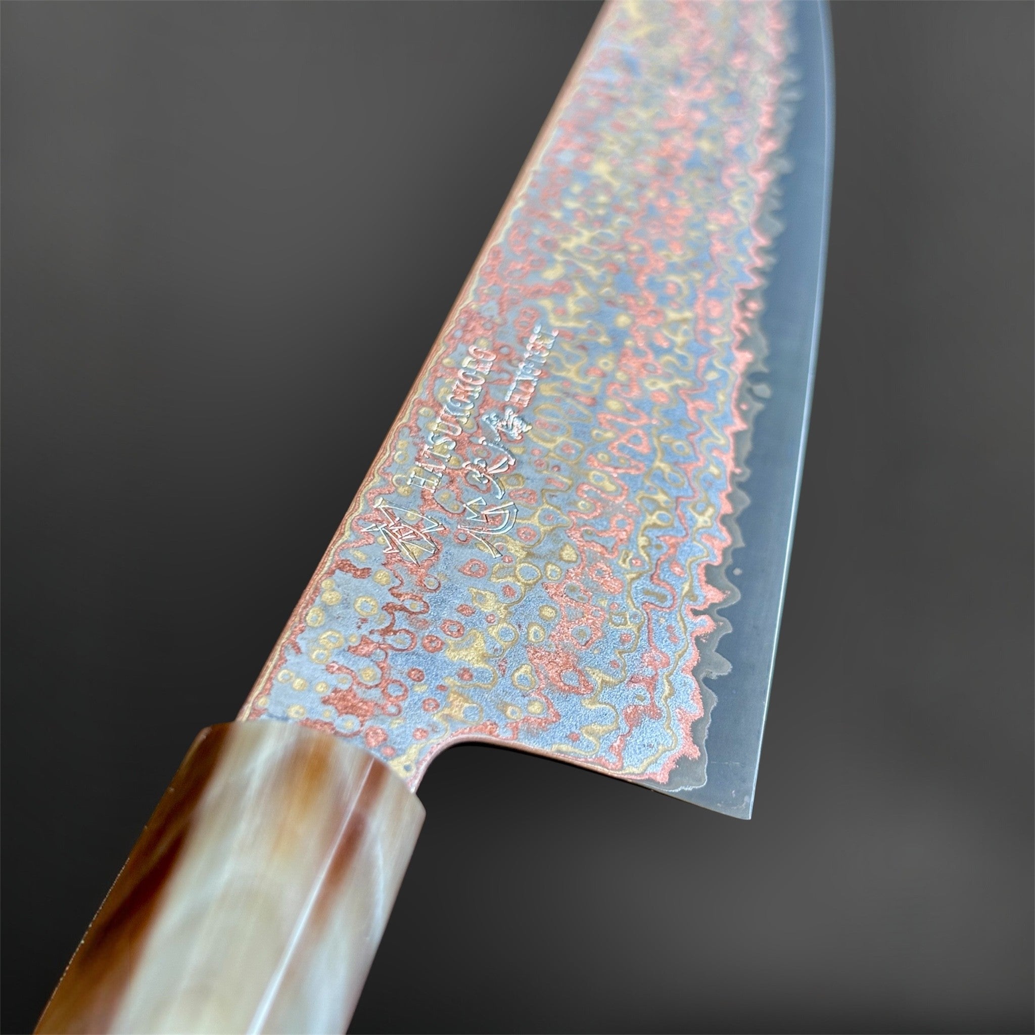 Hatsukokoro Hinotori V-Toku2 Rainbow Damascus Gyuto 240 mm, spine-view close-up showing the thin grind and horn ferrule.