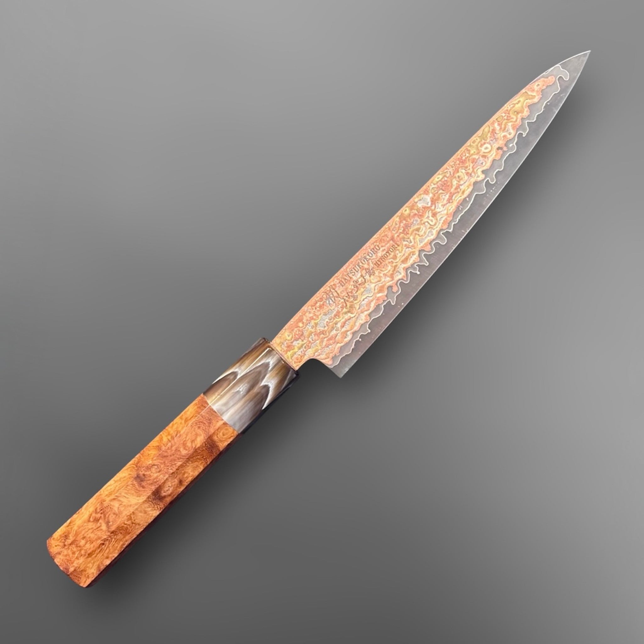 Hatsukokoro Hinotori V-Toku2 Rainbow Damascus Petty 150 mm with Amboyna Burl handle, angled full knife view showing iridescent rainbow Damascus blade.