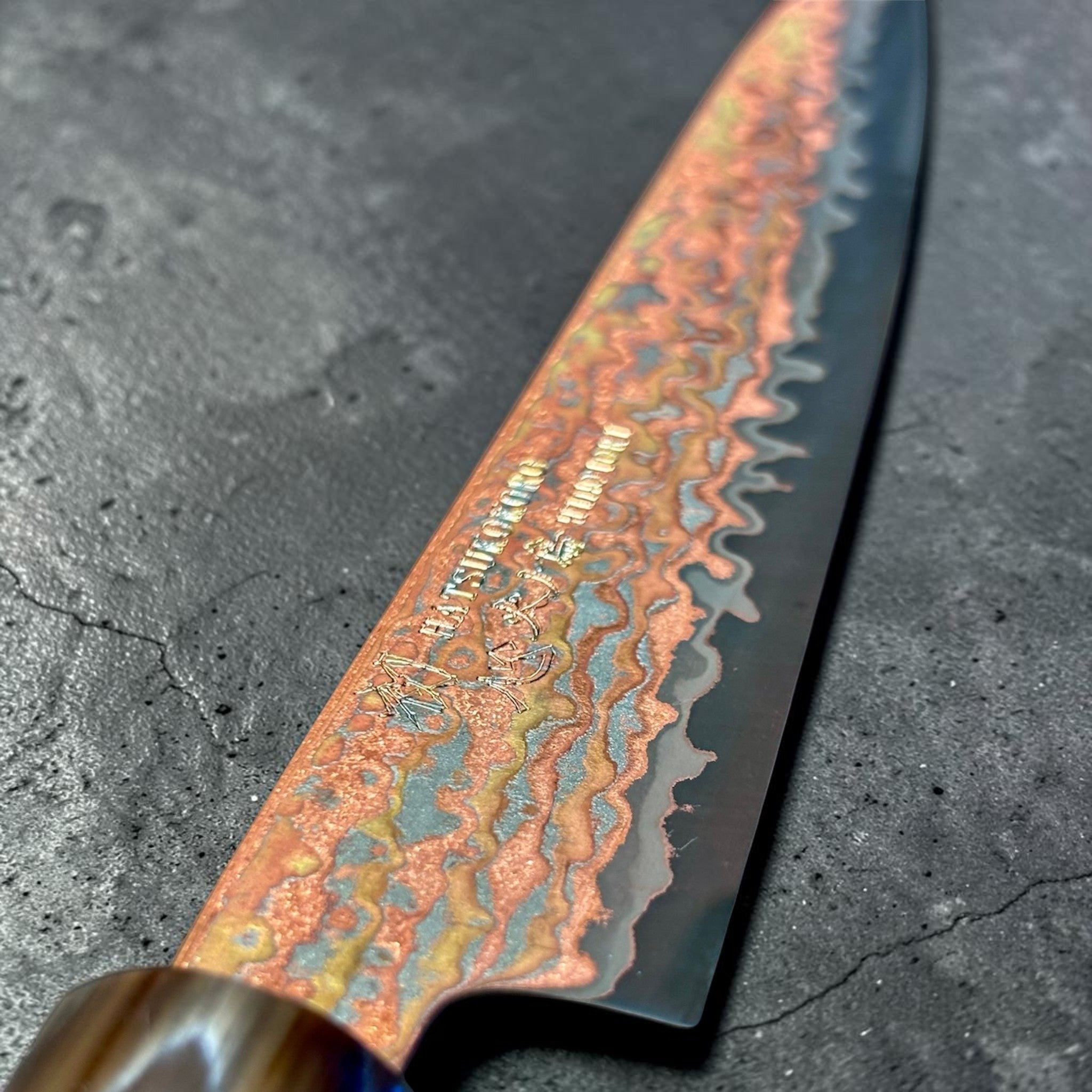 Hatsukokoro Hinotori V-Toku2 Rainbow Damascus Petty 150 mm with Amboyna Burl handle, close-up of engraved rainbow Damascus pattern near the heel.
