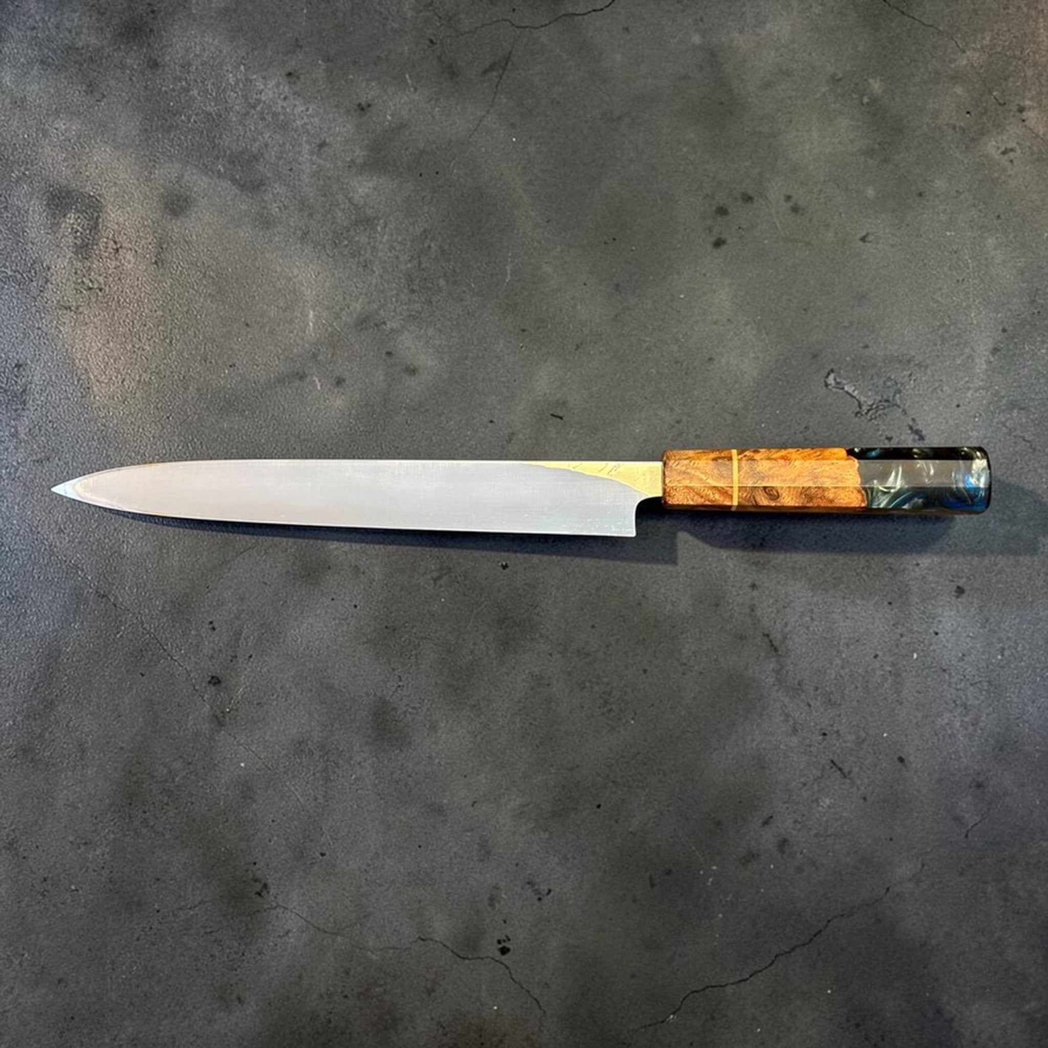 Hatsukokoro Hyomon White #2 Damascus Yanagiba 270 mm with Prisma Knife Handle, full profile view on dark textured background.