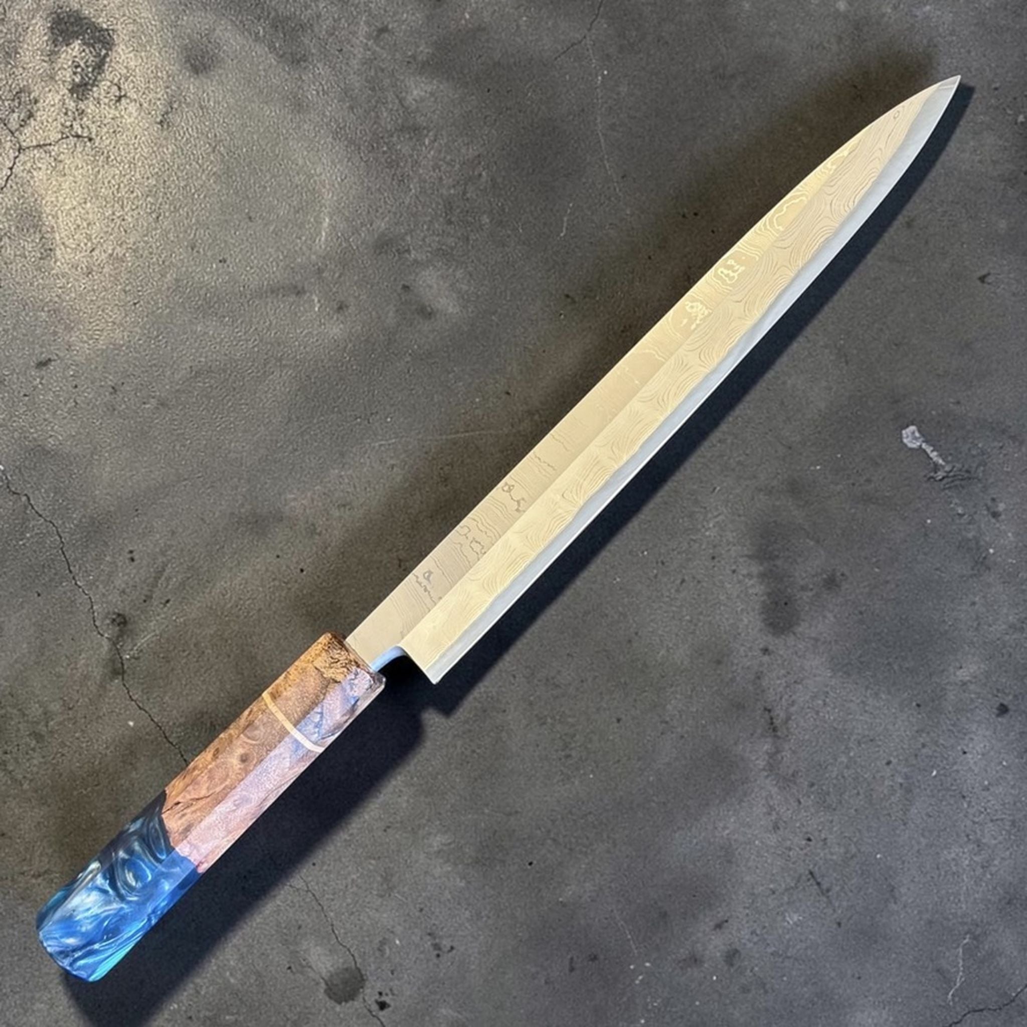 Hatsukokoro Hyomon White #2 Damascus Yanagiba 270 mm with Prisma Knife Handle, angled view showing Damascus pattern and blue resin handle end.