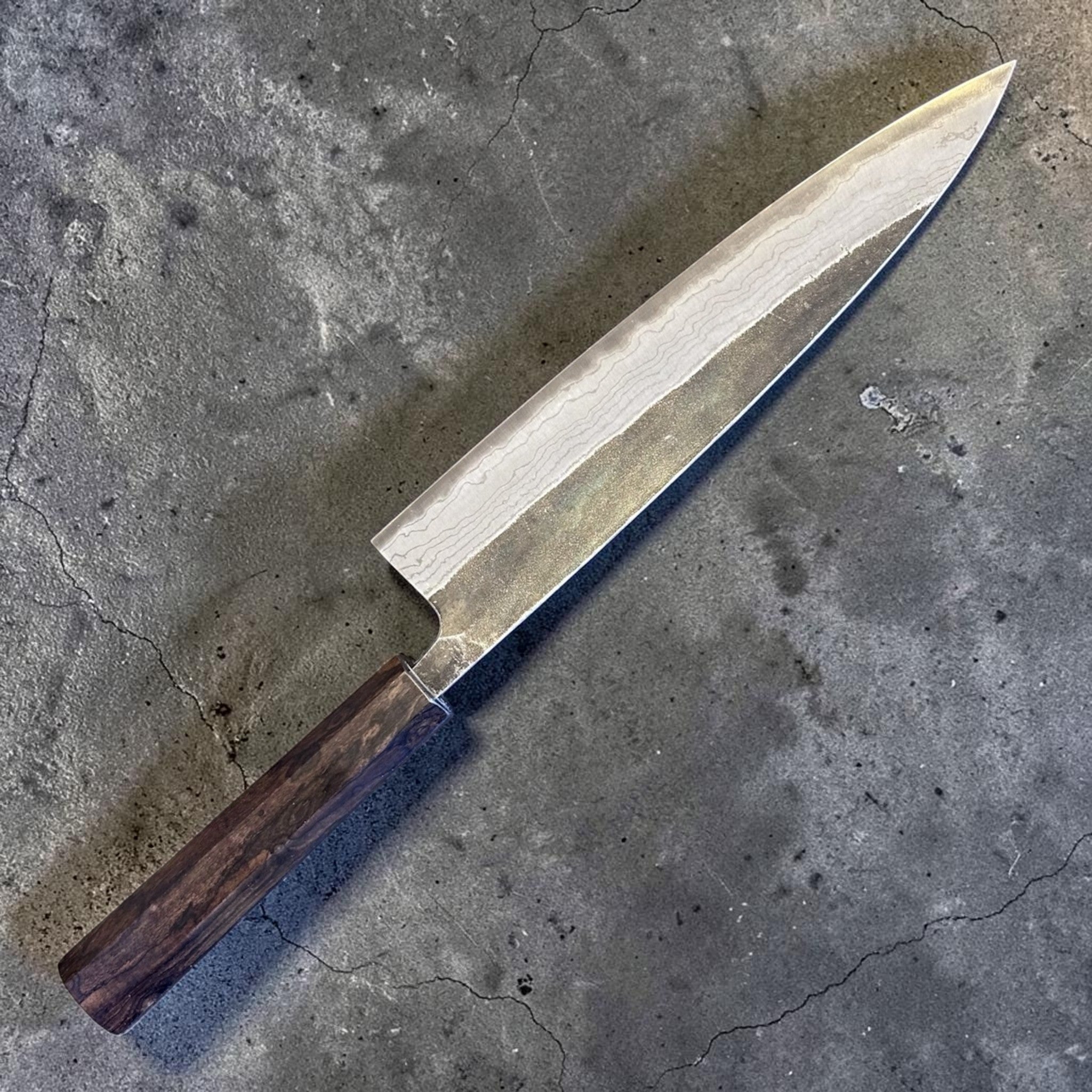 Hatsukokoro Kumokage Blue #2 Gyuto 240 mm with mono ebony handle, angled blade view highlighting the layered finish.