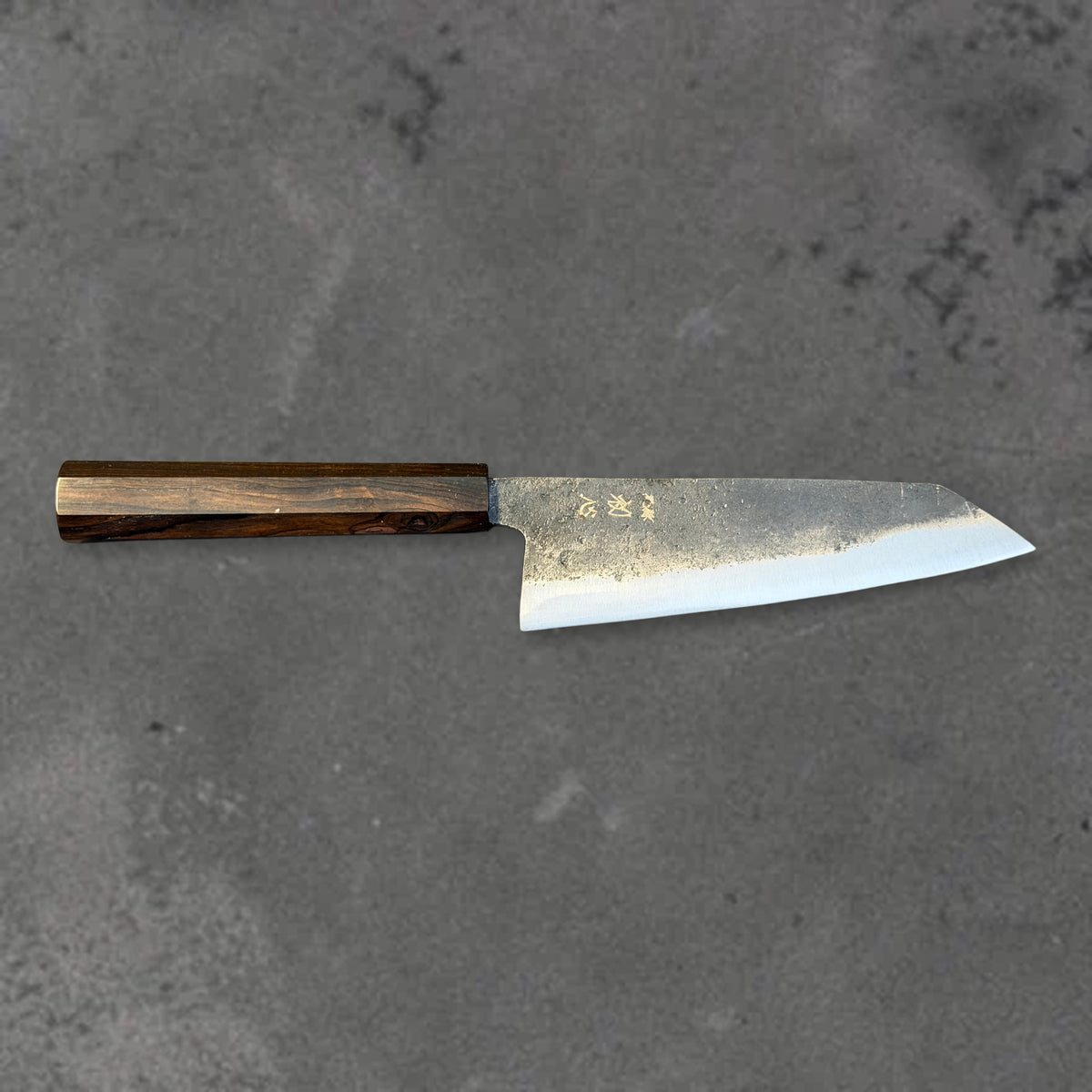 Hatsukokoro Kurogane Blue #2 Kurouchi 140mm bunka with ebony handle, shown in horizontal front profile with the full blade and handle visible.