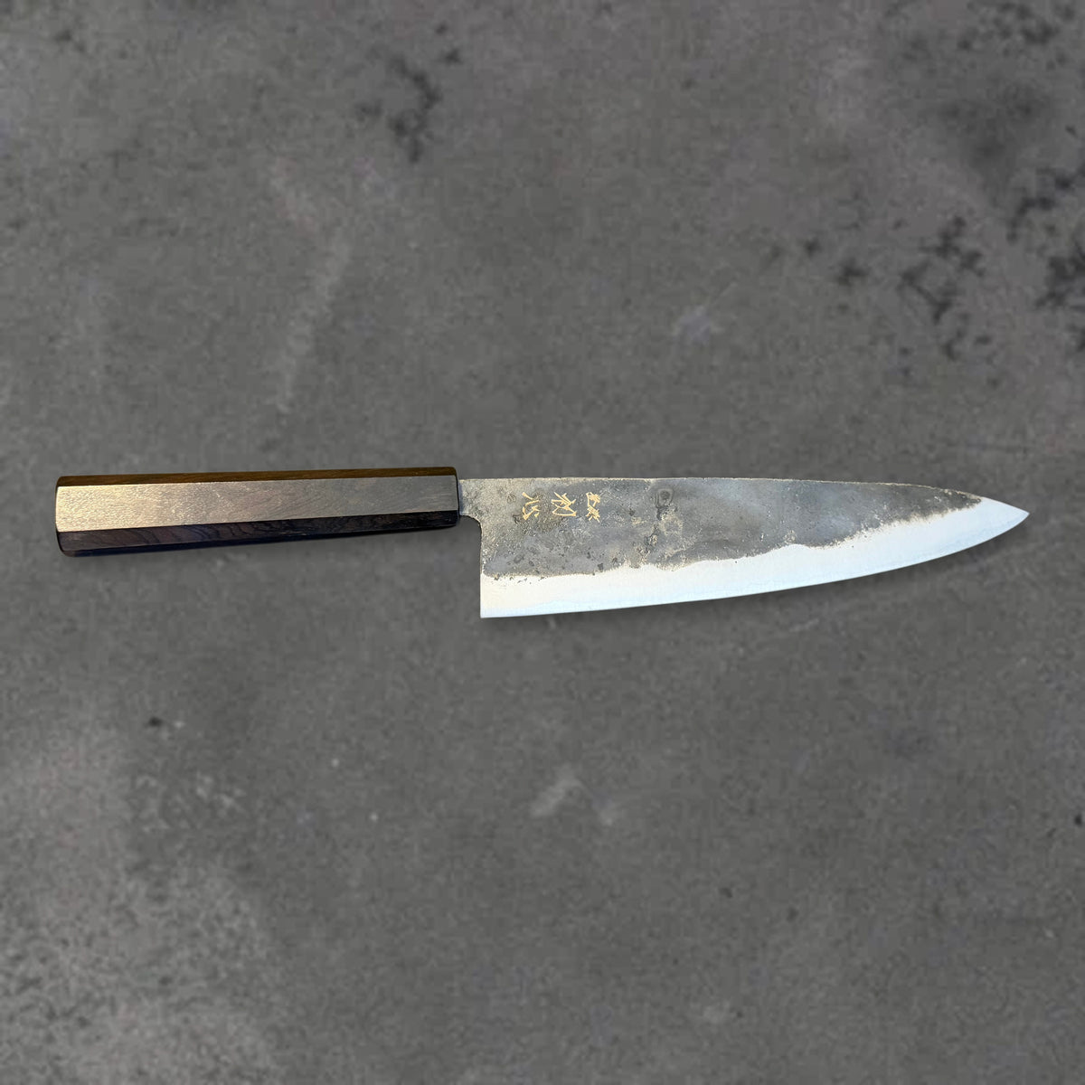 Hatsukokoro Kurogane Blue #2 Kurouchi 210mm gyuto with ebony handle, shown in horizontal front profile with the full blade and handle visible.