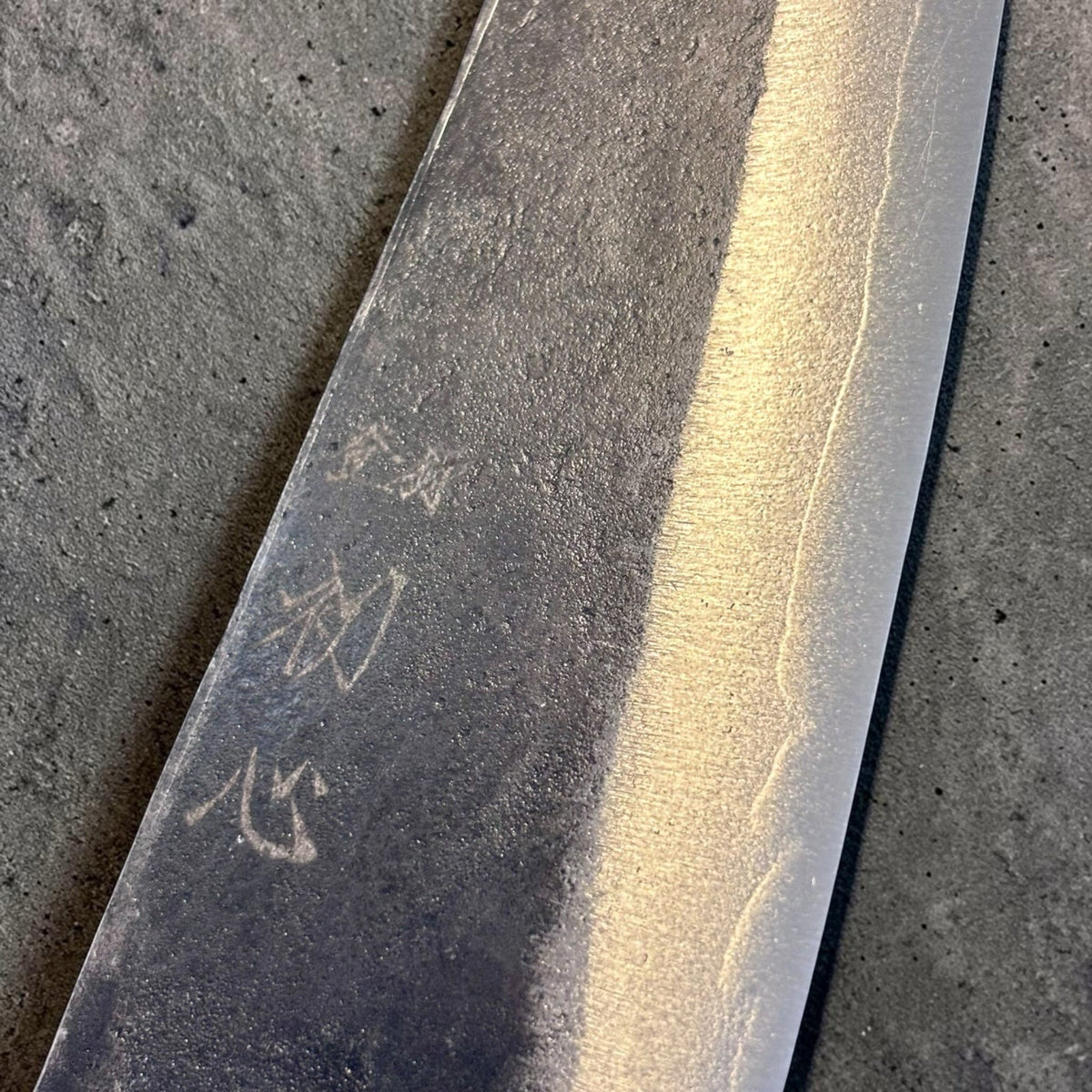 Close-up of kurouchi finish, cladding line, and kanji on Hatsukokoro Kurogane Blue #2 Honesuki