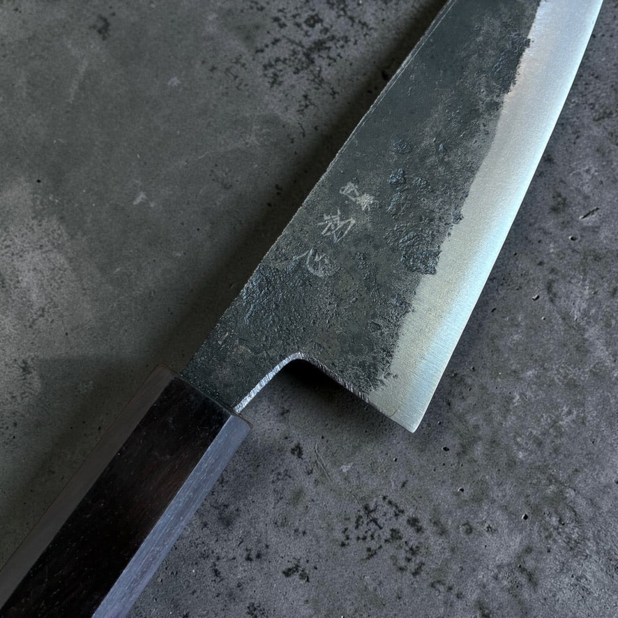 Close-up of the kurouchi blade finish and engraved kanji on the Hatsukokoro Kurogane Blue #2 Honesuki.