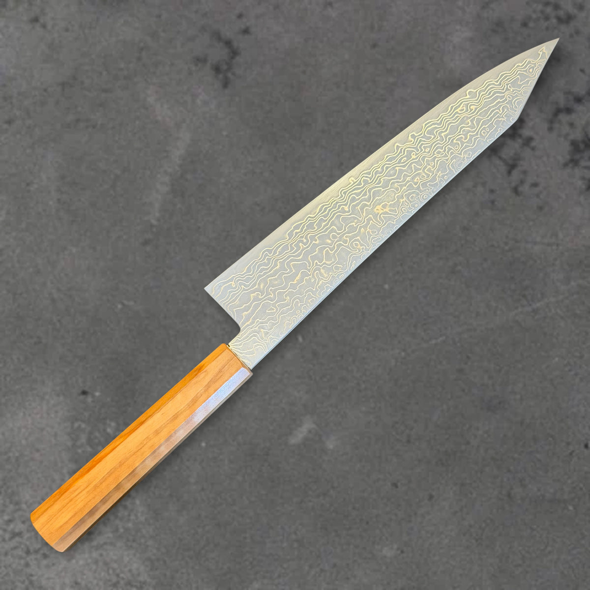 Angled reverse view of the Hatsukokoro Ryuhyo SG2 Damascus 210mm kiritsuke with olive wood handle, showing the blade shape, finish, and handle.