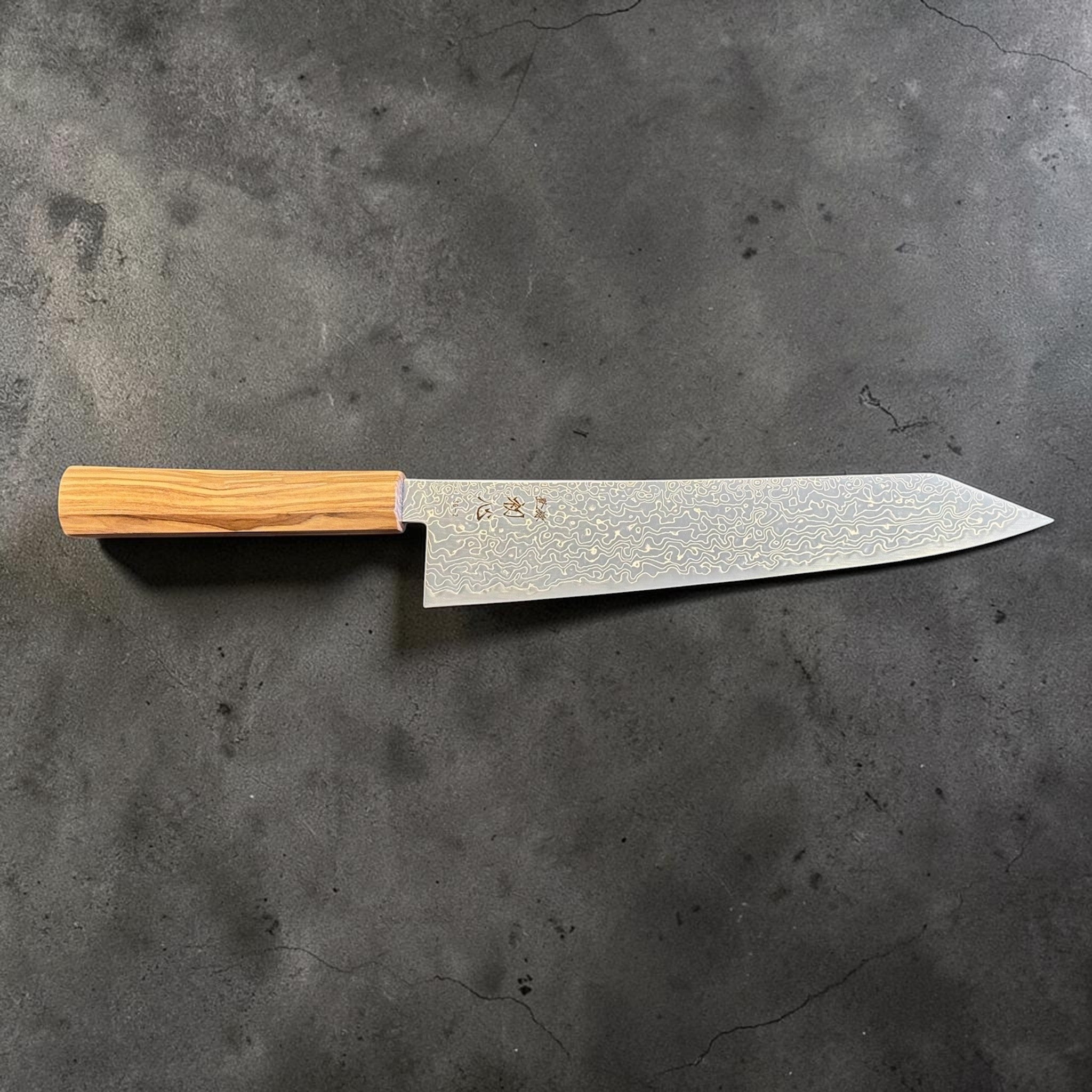 Hatsukokoro Ryuhyo SG2 Damascus Migaki Kiritsuke 240 mm with olive wood handle, full side profile showing the thin kiritsuke blade, flat edge line, and pale olive wood handle grain.