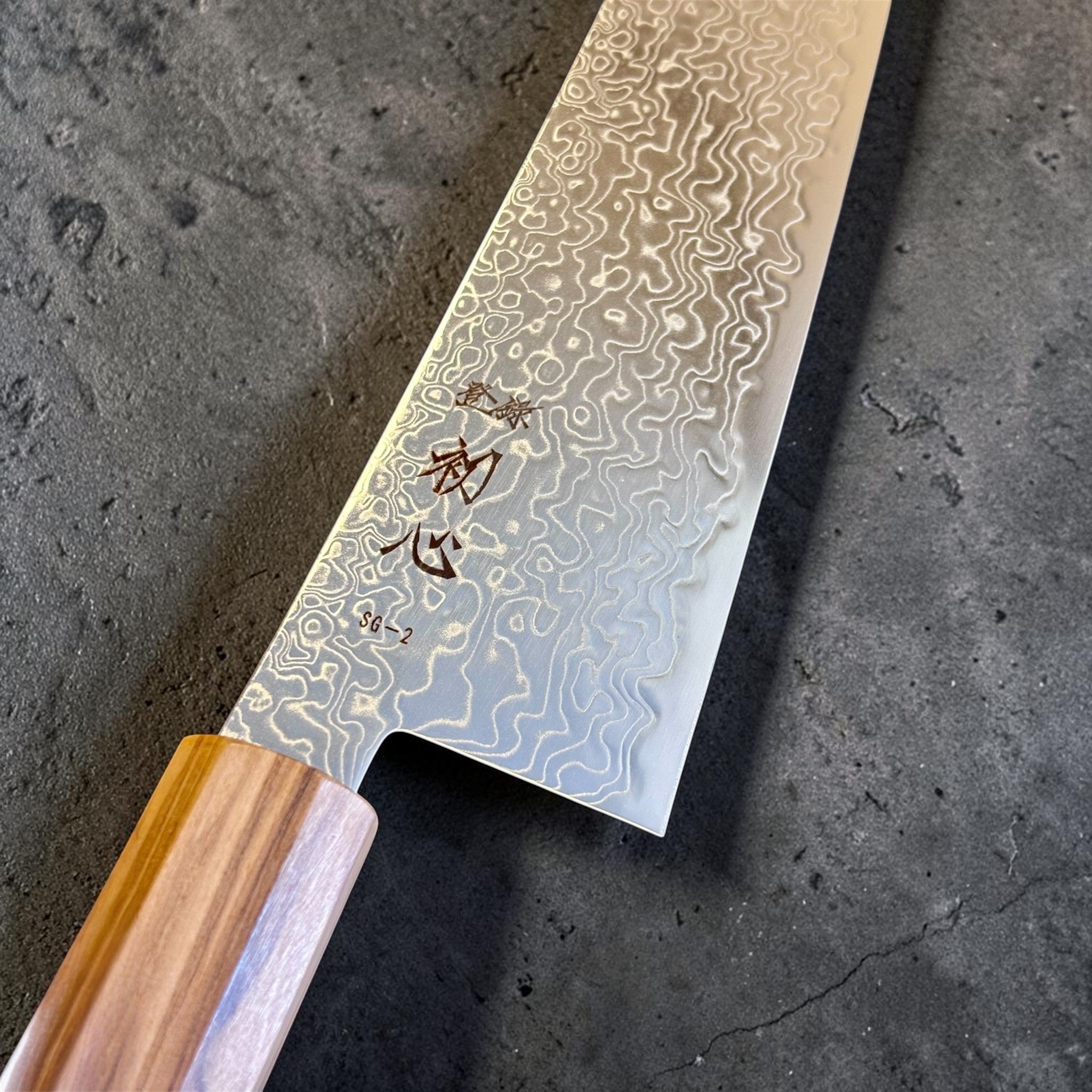 Hatsukokoro Ryuhyo SG2 Damascus Migaki Kiritsuke 240 mm, close-up of the kanji, SG2 core steel area, and high-contrast Damascus pattern near the heel.