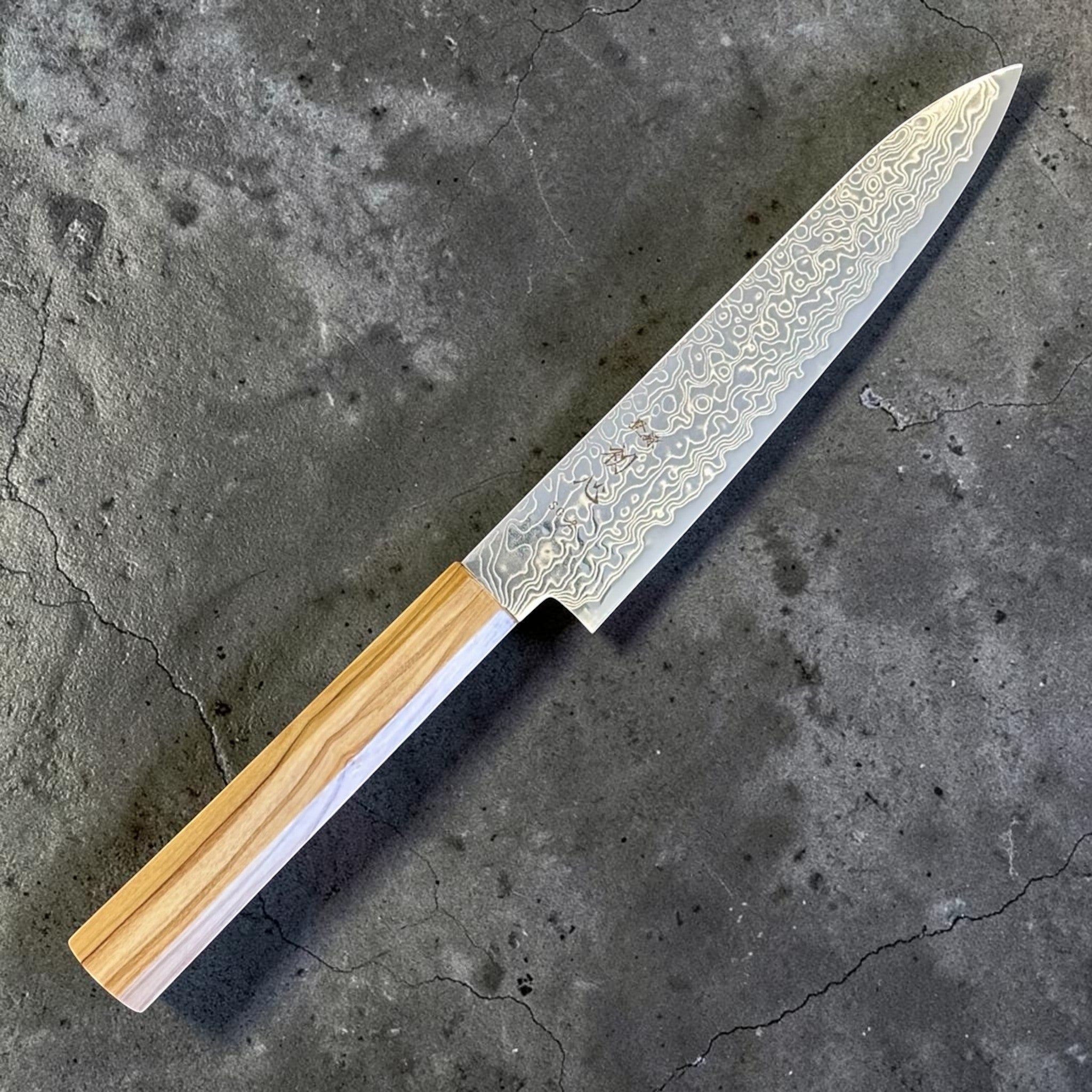 Hatsukokoro Ryuhyo SG2 Damascus Petty 150 mm with olive wood handle, angled view highlighting the pointed petty profile and layered blade finish.