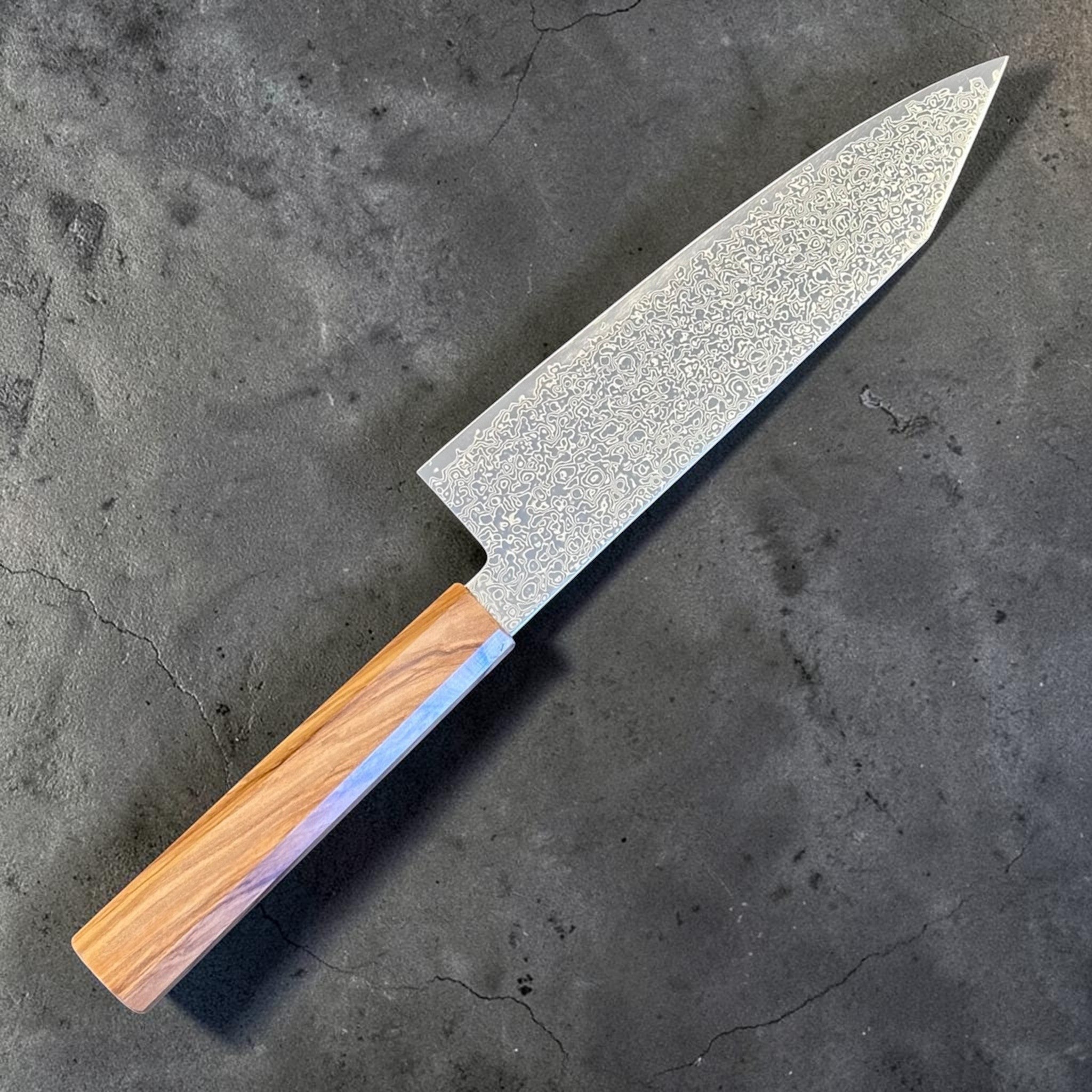 Hatsukokoro Saihyo SG2 Damascus Bunka 180 mm with olivewood handle, angled rear-side view showing the blade face and octagonal handle.