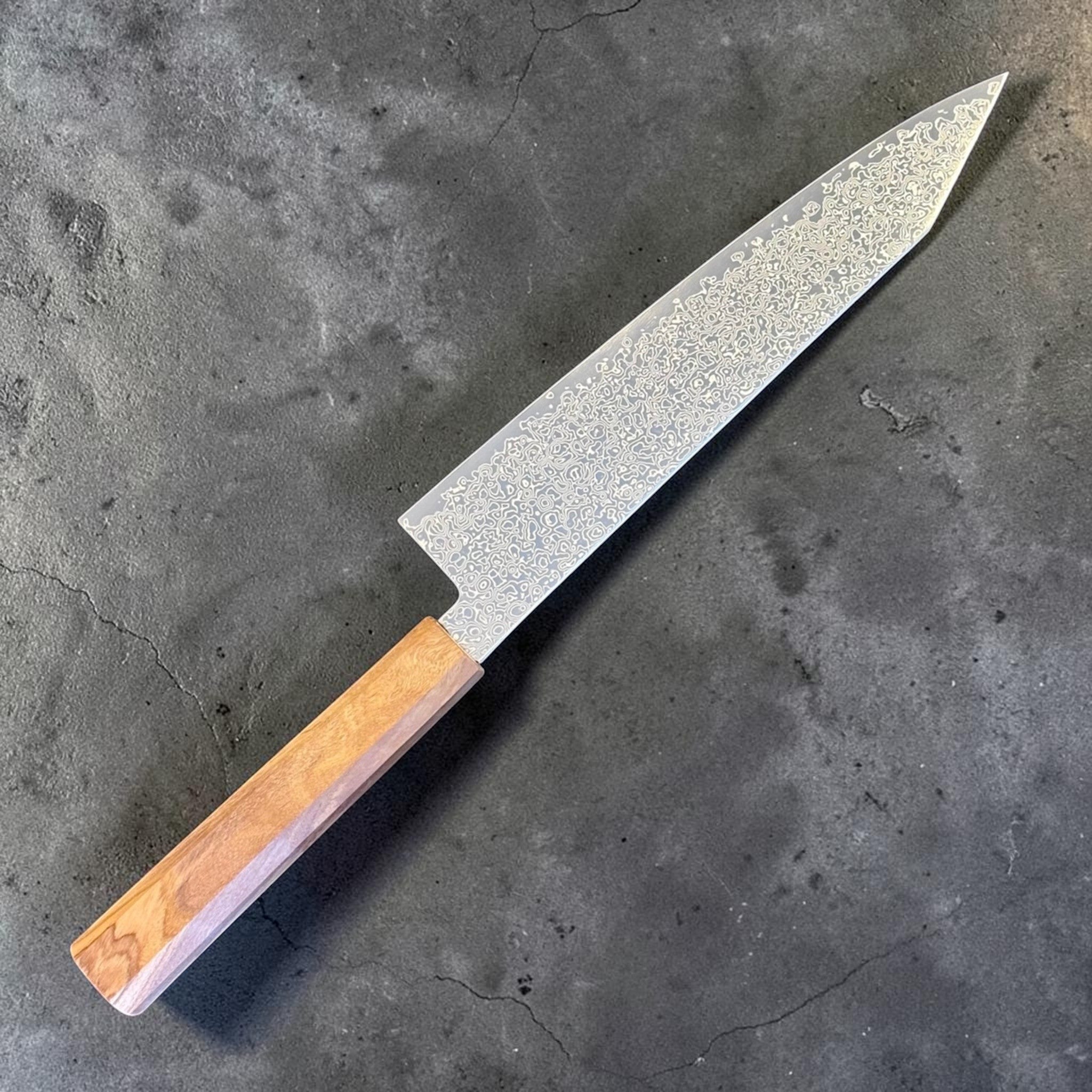 Hatsukokoro Saihyo SG2 Damascus Kiritsuke 210 mm with mono olive handle, angled left side view.