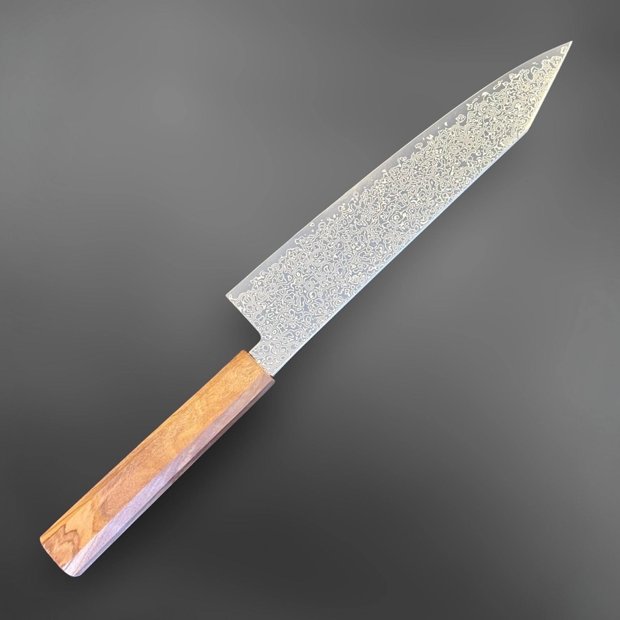 Hatsukokoro Saihyo SG2 Damascus Kiritsuke 210 mm with mono olive handle, angled left side view.