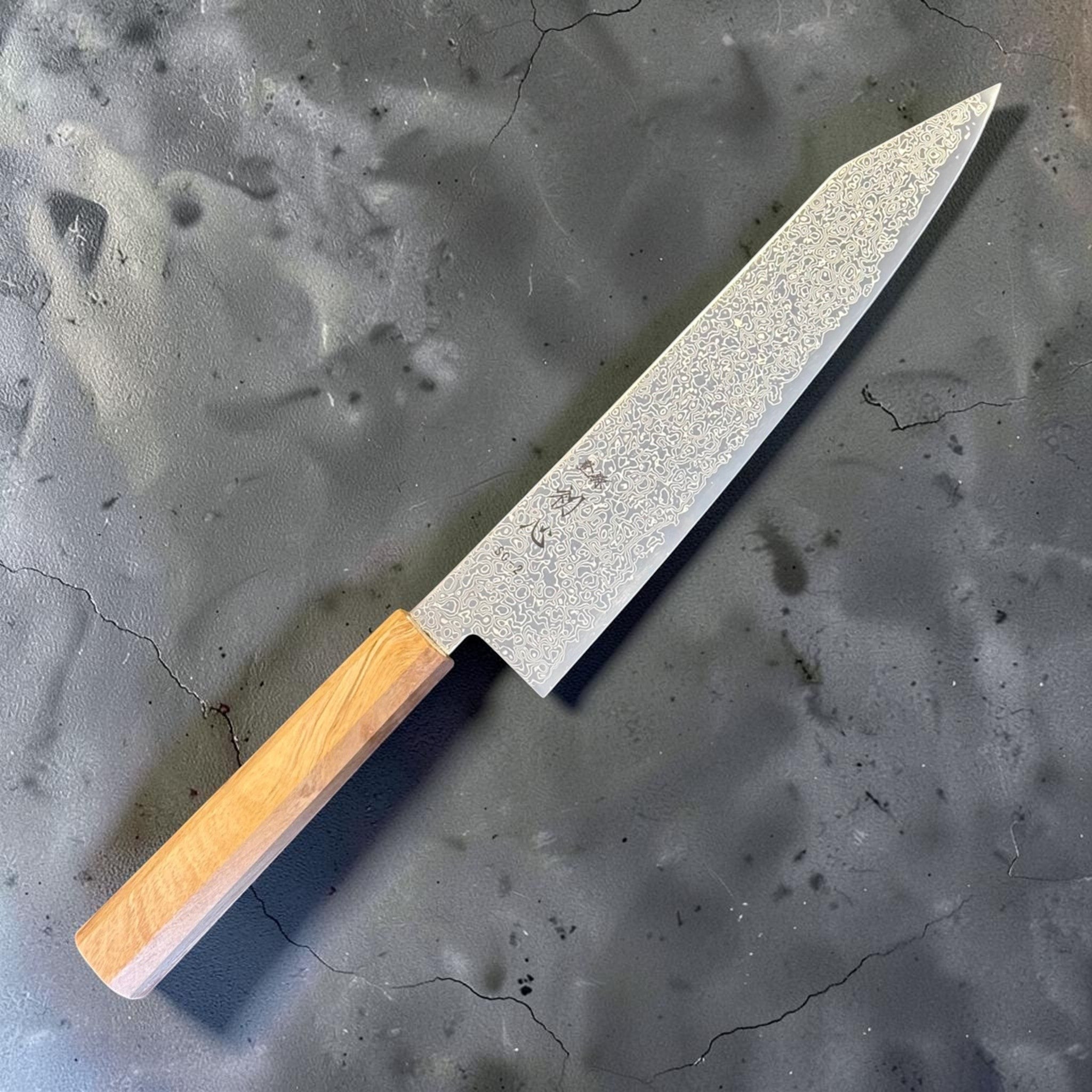 Hatsukokoro Saihyo SG2 Damascus Kiritsuke 210 mm with mono olive handle, angled logo-side view.