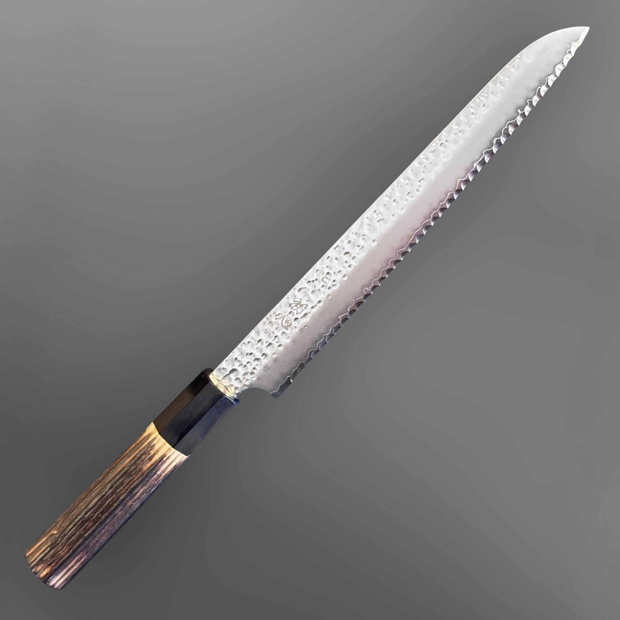 Hatsukokoro VG-10 Tsuchime Serrated Bread Knife 230 mm with burnt wood and black buffalo horn handle, angled product view highlighting the serrated edge and hammered blade finish.