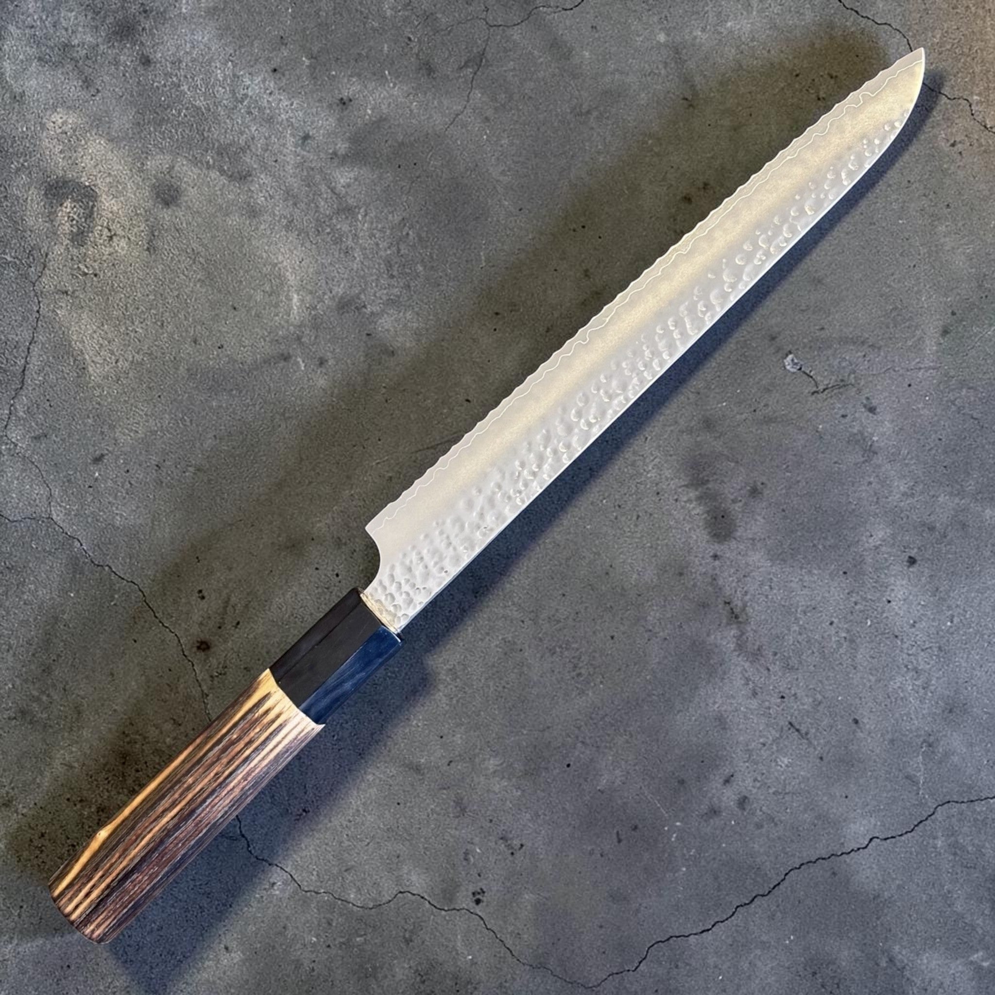 Hatsukokoro VG-10 Tsuchime Serrated Bread Knife 230 mm with burnt wood and black buffalo horn handle, angled product view showing the full blade profile, burnt wood handle, and black buffalo horn ferrule.