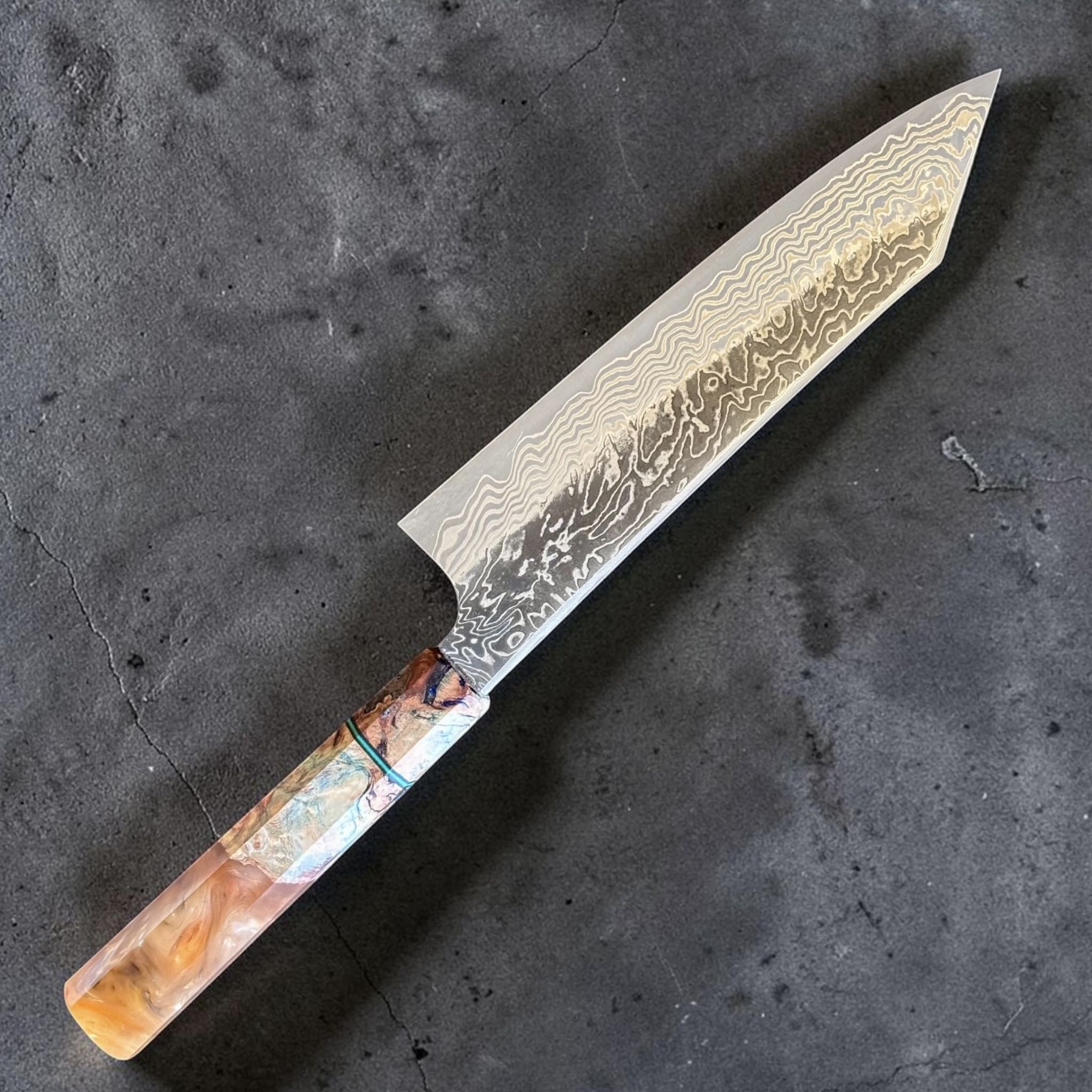 Hatsukokoro Yorokobi Kurouchi Damascus Blast Kiritsuke Gyuto 210 mm with Prisma knife handle, angled full knife view showing Damascus blade pattern.