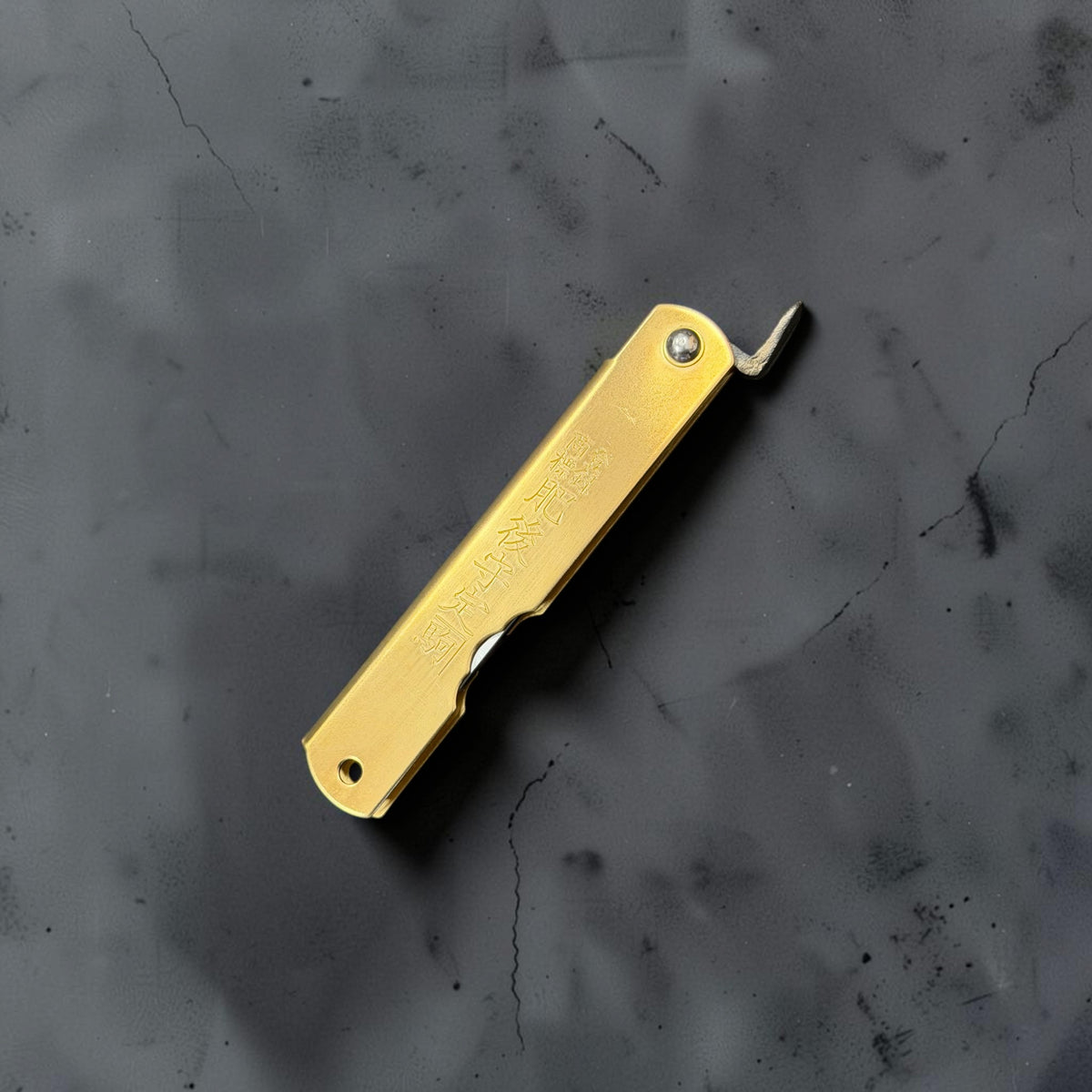 Higonokami Blue #2 medium pocket knife closed, showing stamped brass handle, lanyard hole and chikiri lever.
