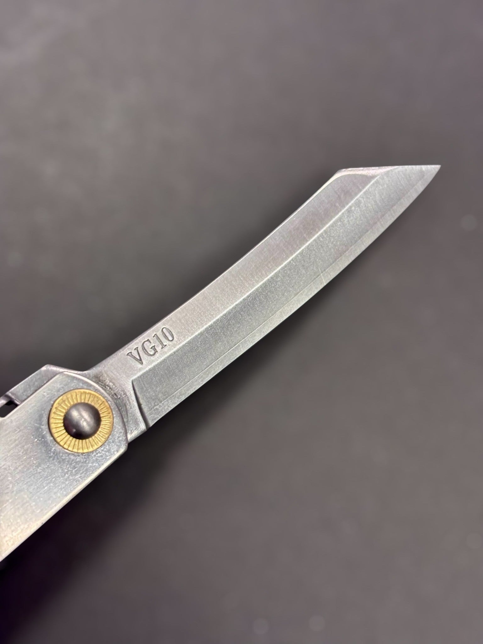 Close‑up of VG‑10 steel kiritsuke tip on Higonokami pocket knife.