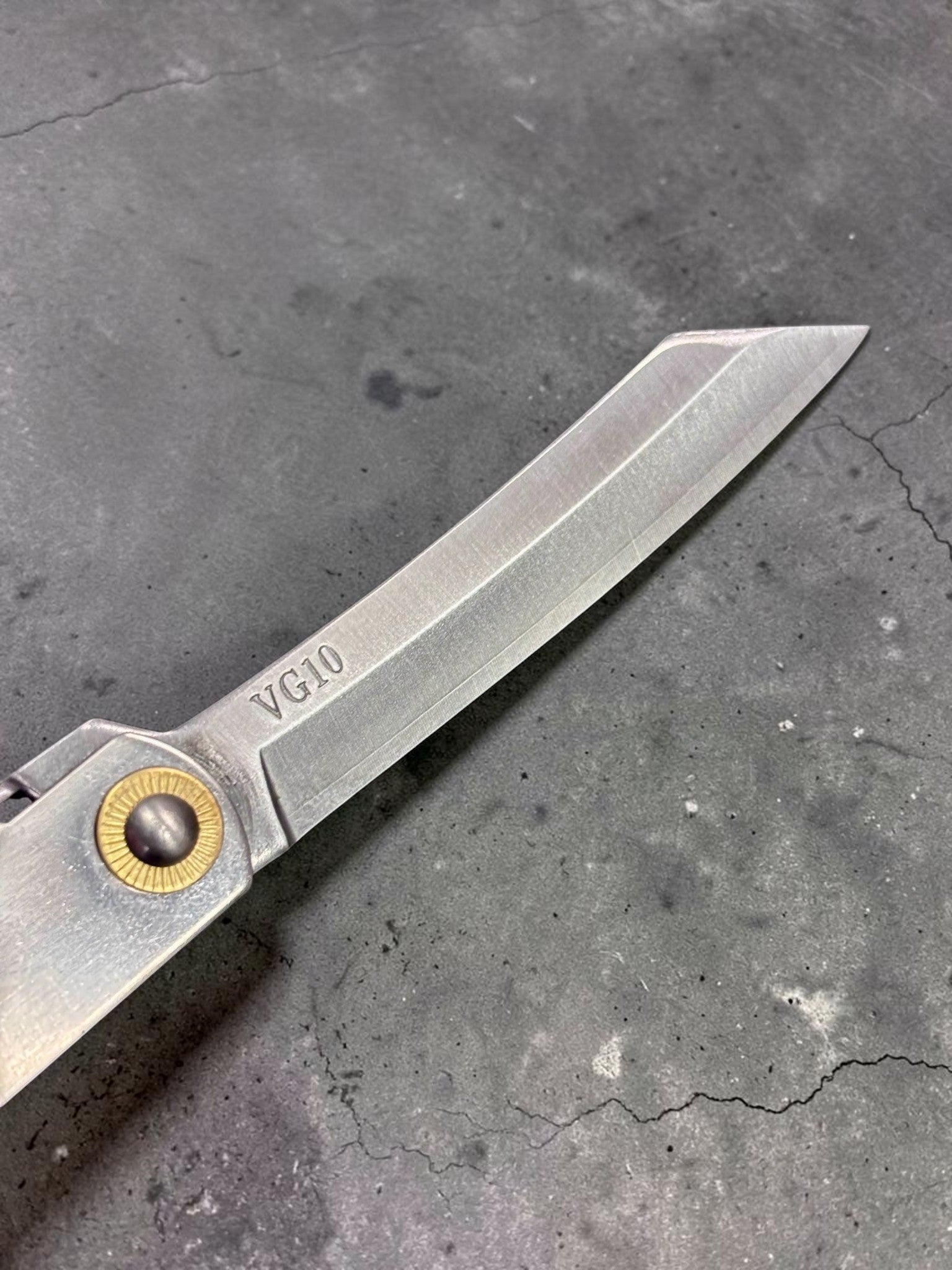Close‑up of VG‑10 steel kiritsuke tip on Higonokami pocket knife.