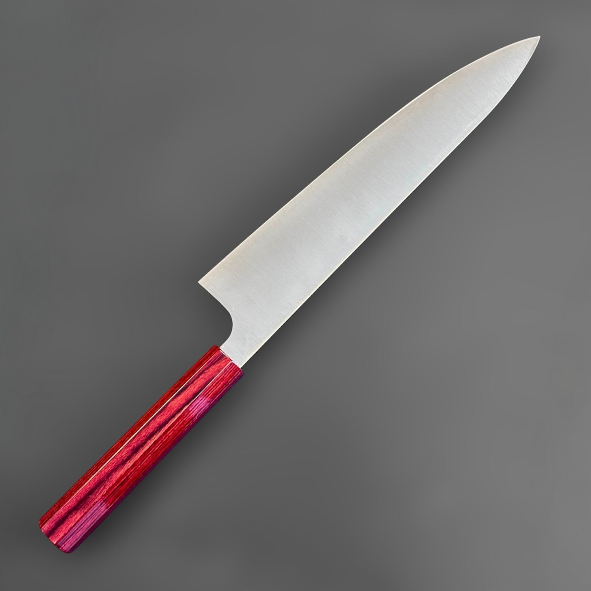 shi SG2 Gyuto 240 mm with red lacquer handle, angled reverse-side view emphasizing the extra-long gyuto profile, thin grind, and distal taper.