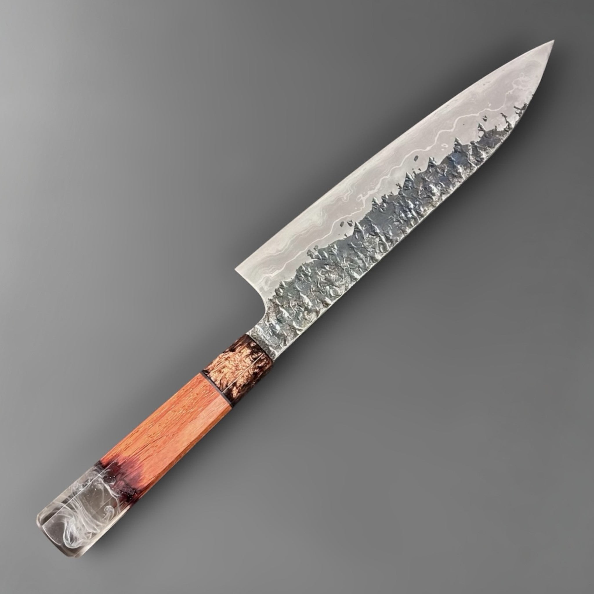 Kisuke Manaka ENN Gyuto 210 mm with Prisma Knife handle, angled full-length view showing the textured kurouchi-style blade finish and orange resin handle.