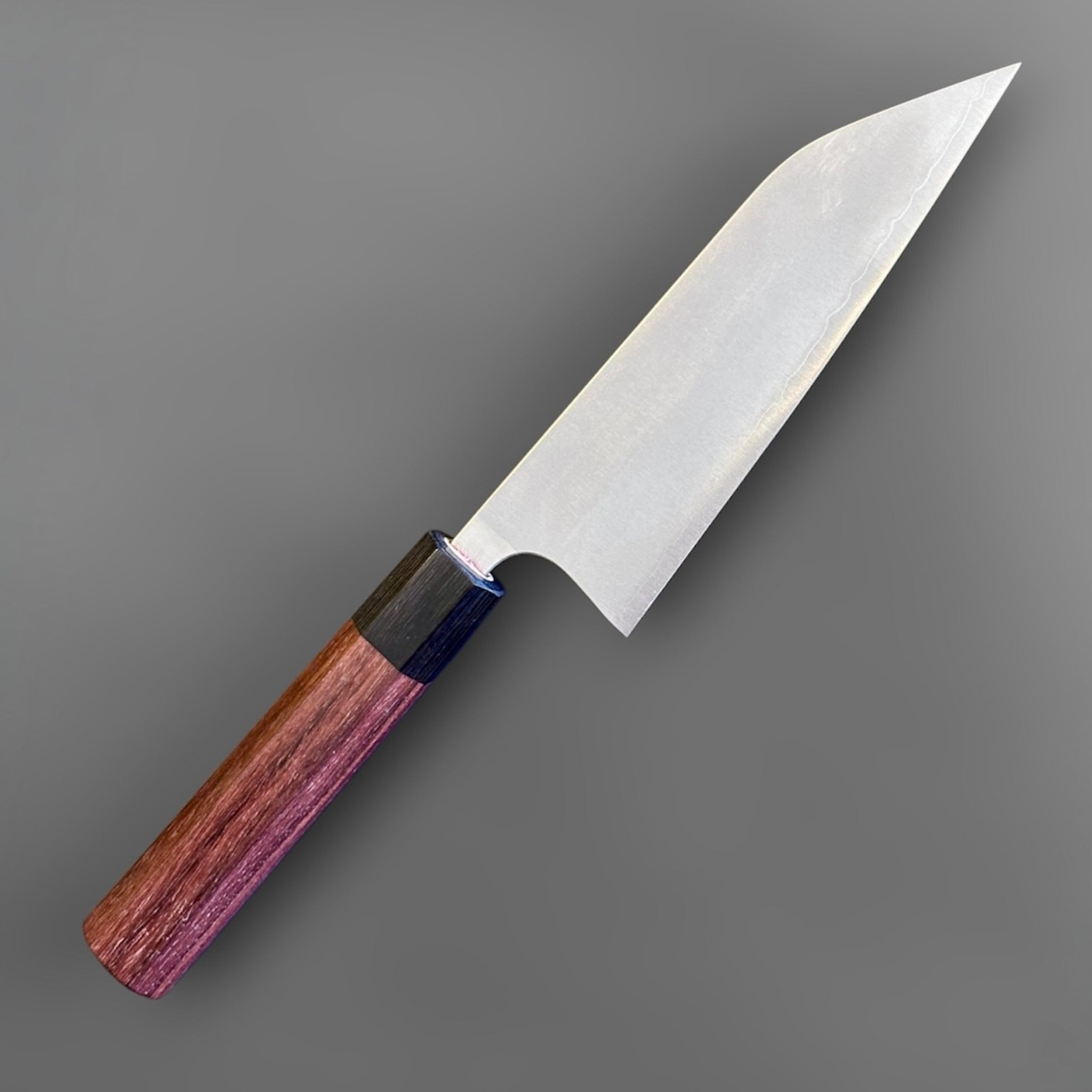Koutetsu Chromax Santoku with rosewood octagon handle, angled front-side close-up showing the compact santoku profile, satin blade finish, and dark ferrule.