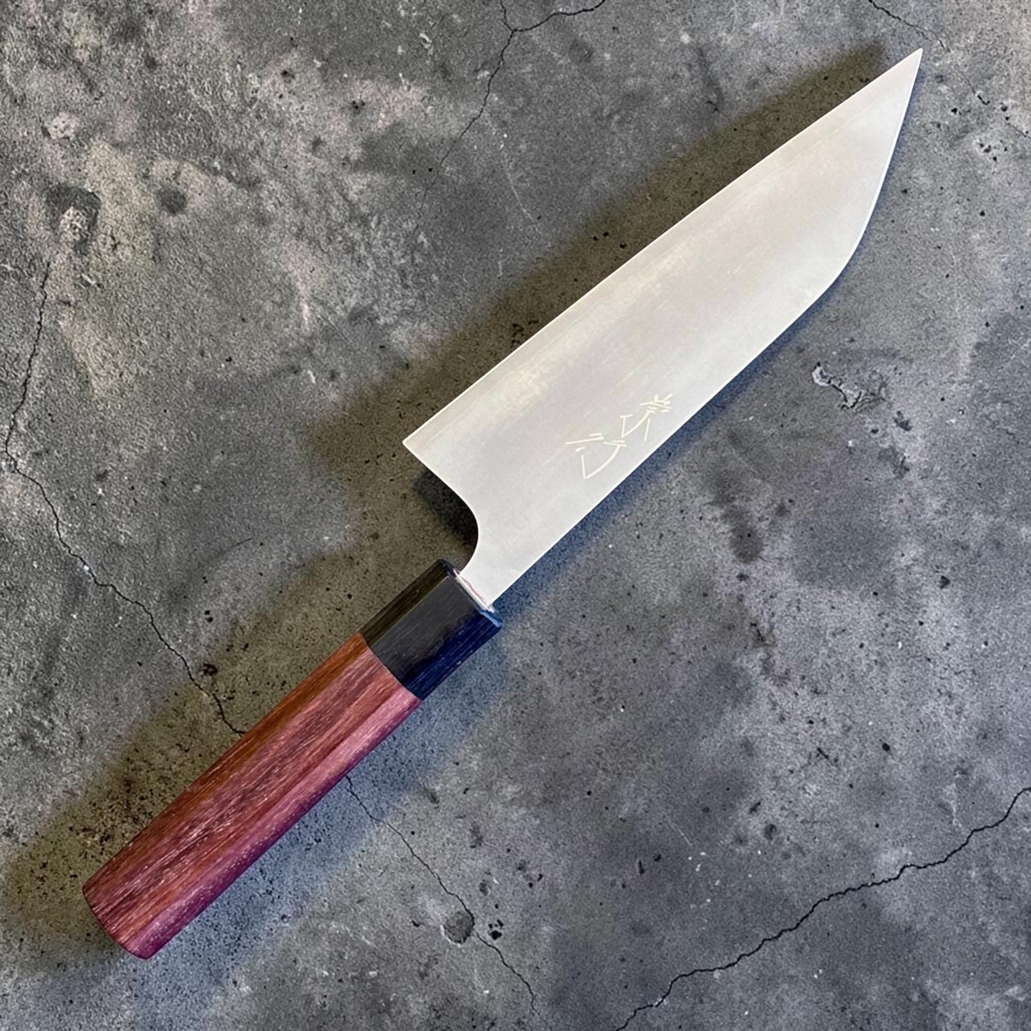 Koutetsu Chromax Santoku with rosewood octagon handle, angled reverse-side view highlighting the clean blade face, engraved kanji, and rosewood wa handle.