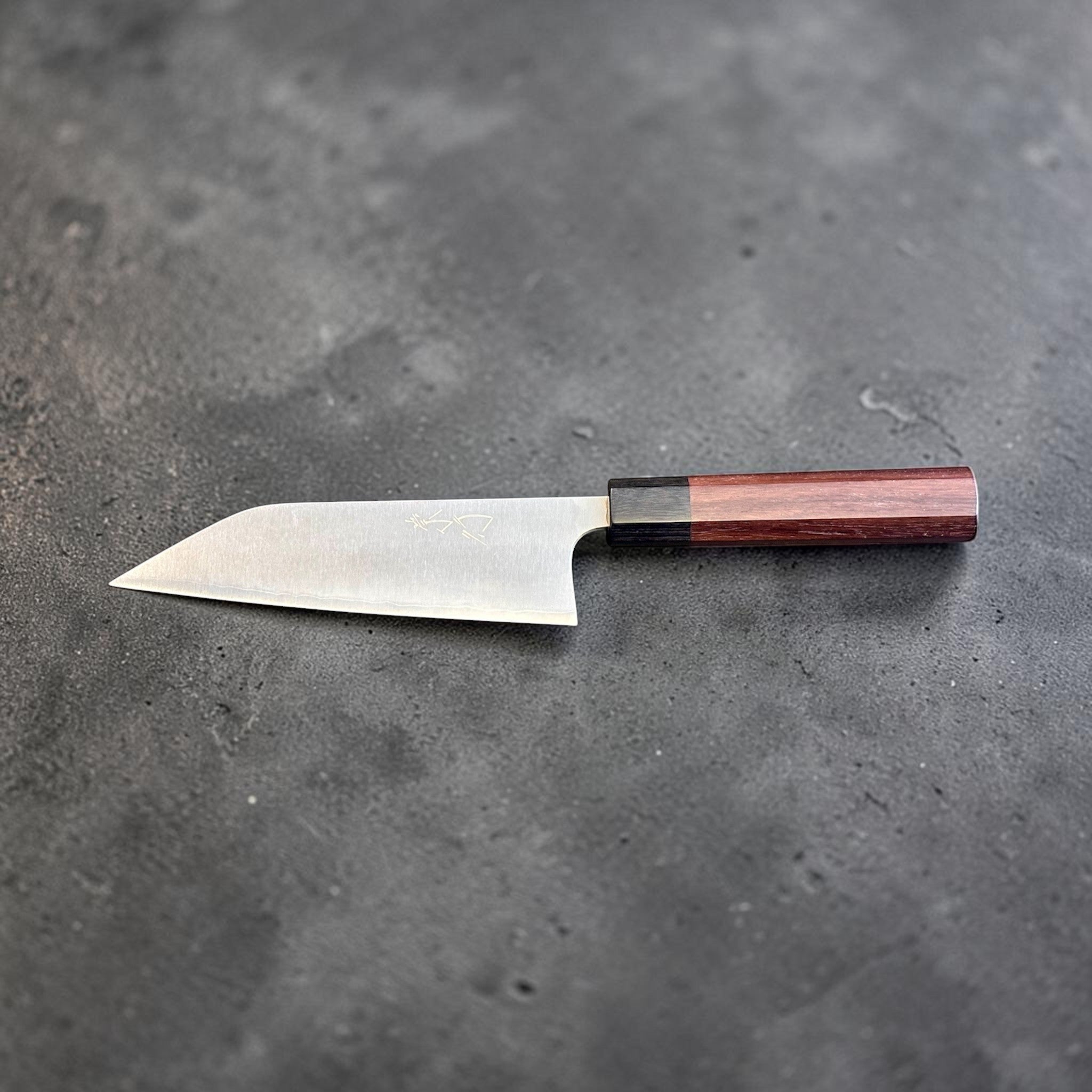 Koutetsu Chromax Santoku with rosewood octagon handle, full reverse-side profile emphasizing the straight edge line, angled tip, and minimalist blade finish.