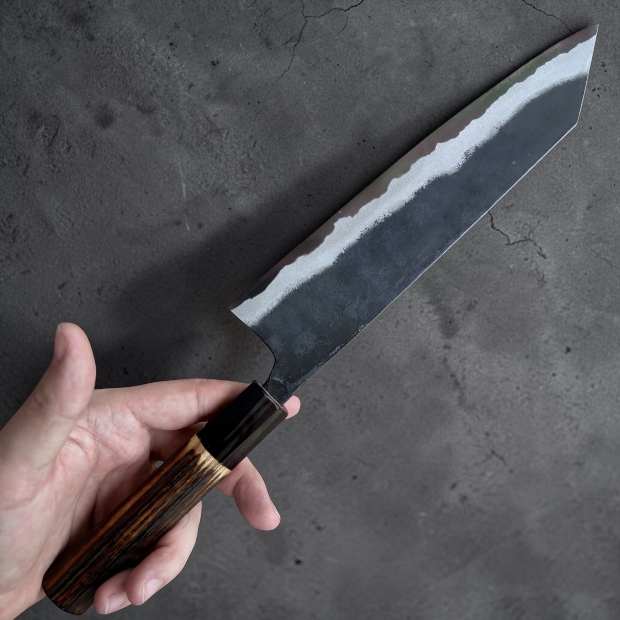 Kyohei Shindo Blue #2 Kurouchi Kiritsuke 210 mm with burnt wood handle and buffalo horn ferrule, choil view showing blade geometry.