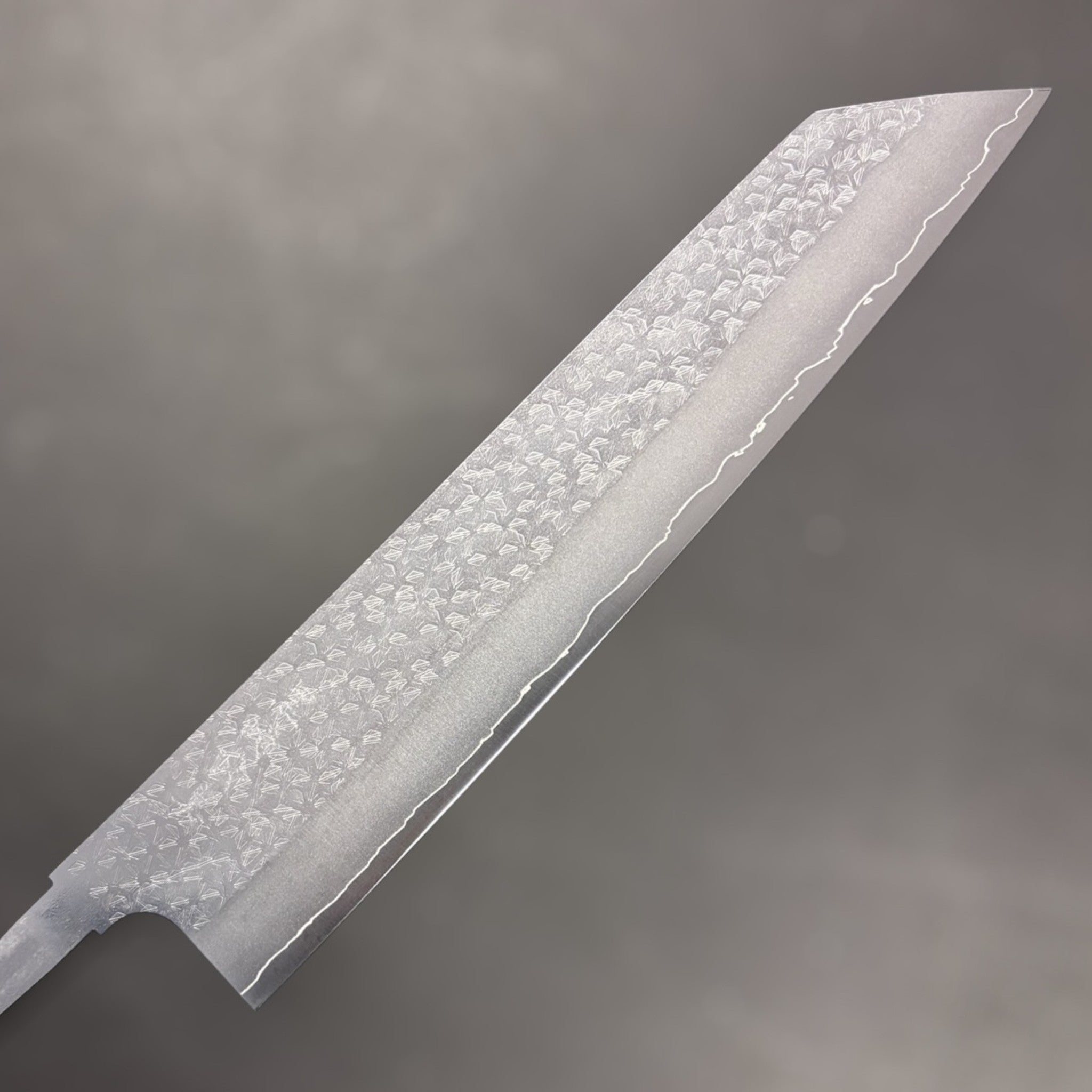 Makoto Kurosaki VG-XEOS Tsuchime Bunka 240 mm blade, close-up of hammered tsuchime pattern and hamon line toward the tip.