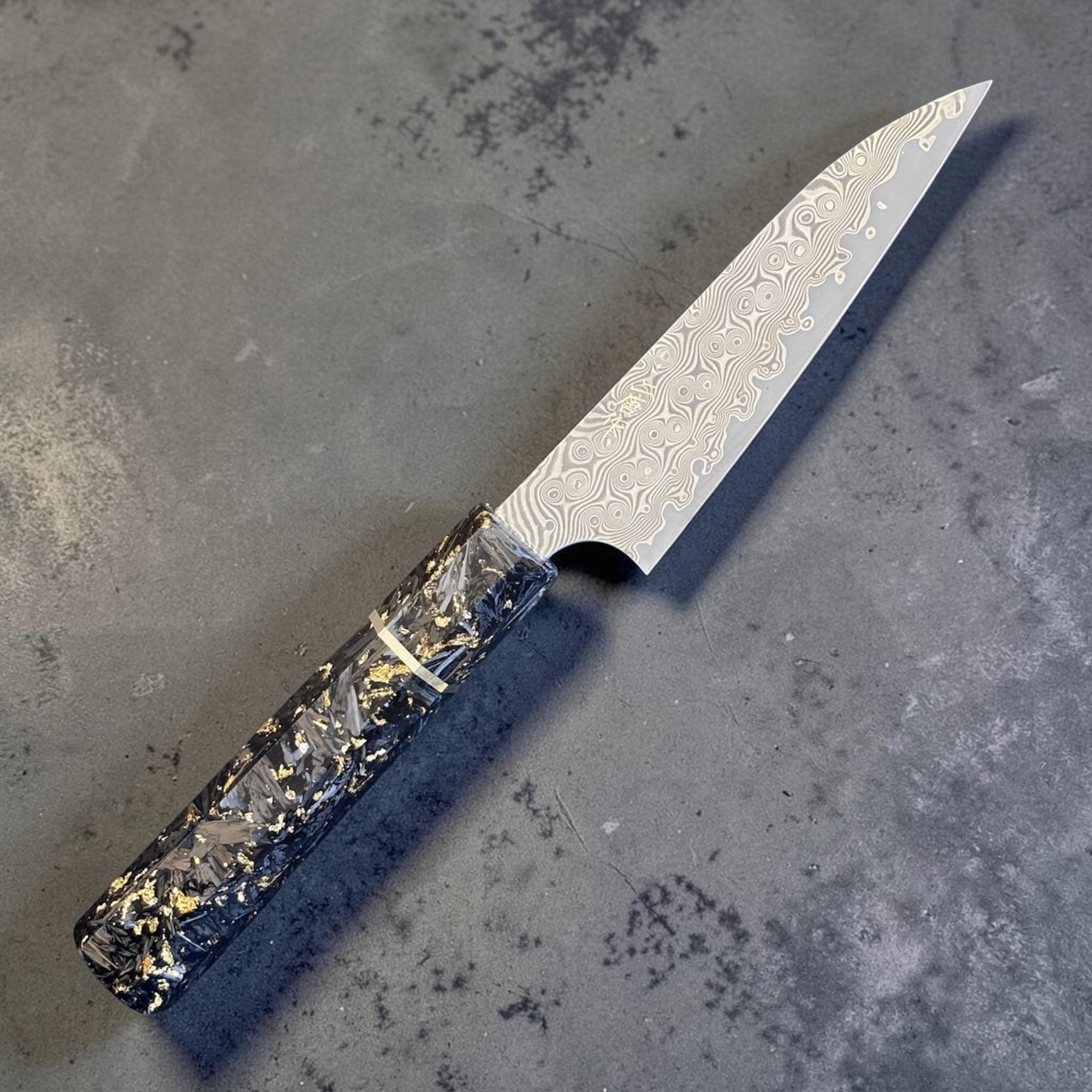 Nigara Anmon SG2 Petty 120 mm with carbon fiber and gold fleck handle, angled full-knife view showing the damascus pattern.